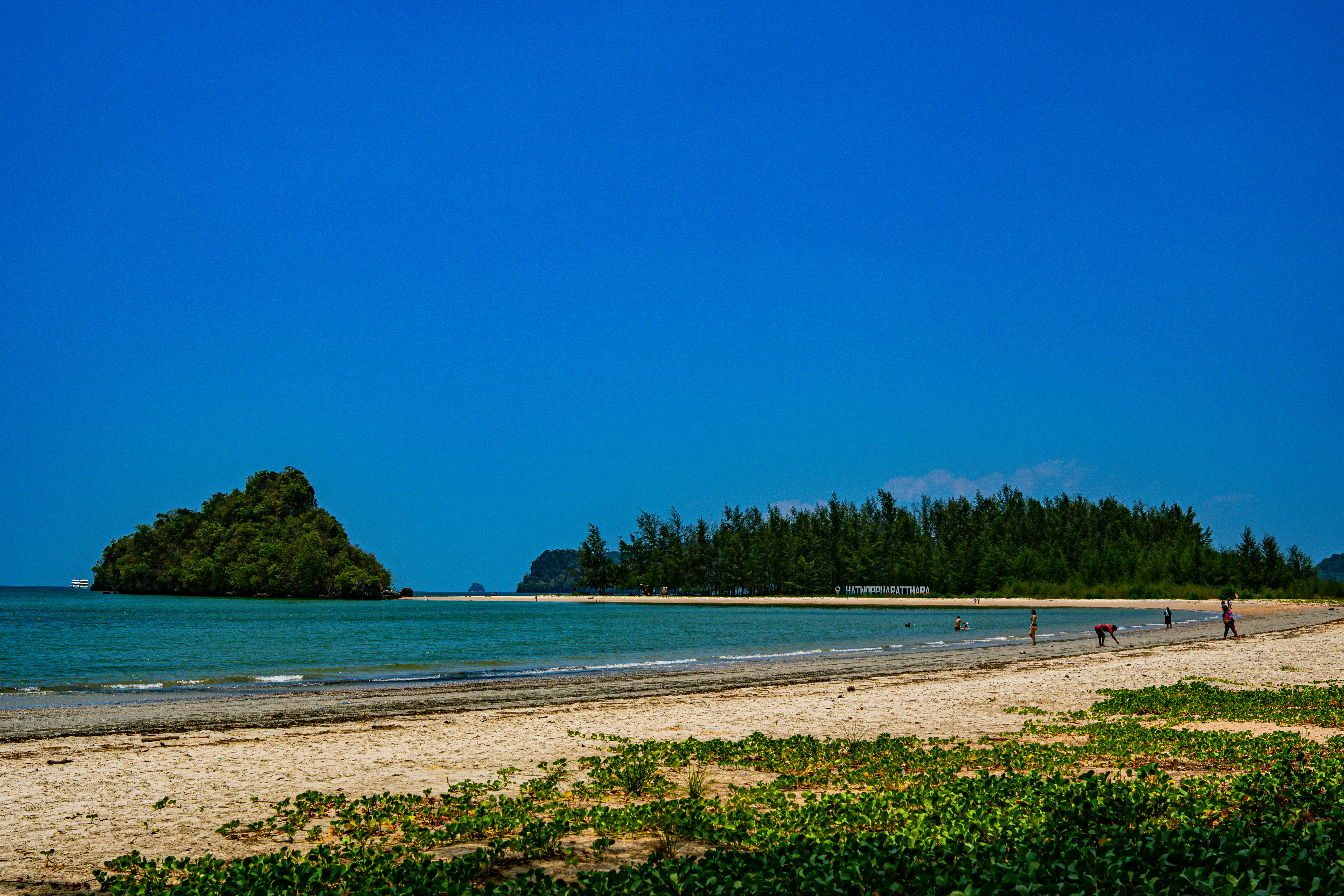 A sandy beach with a small island in the distance