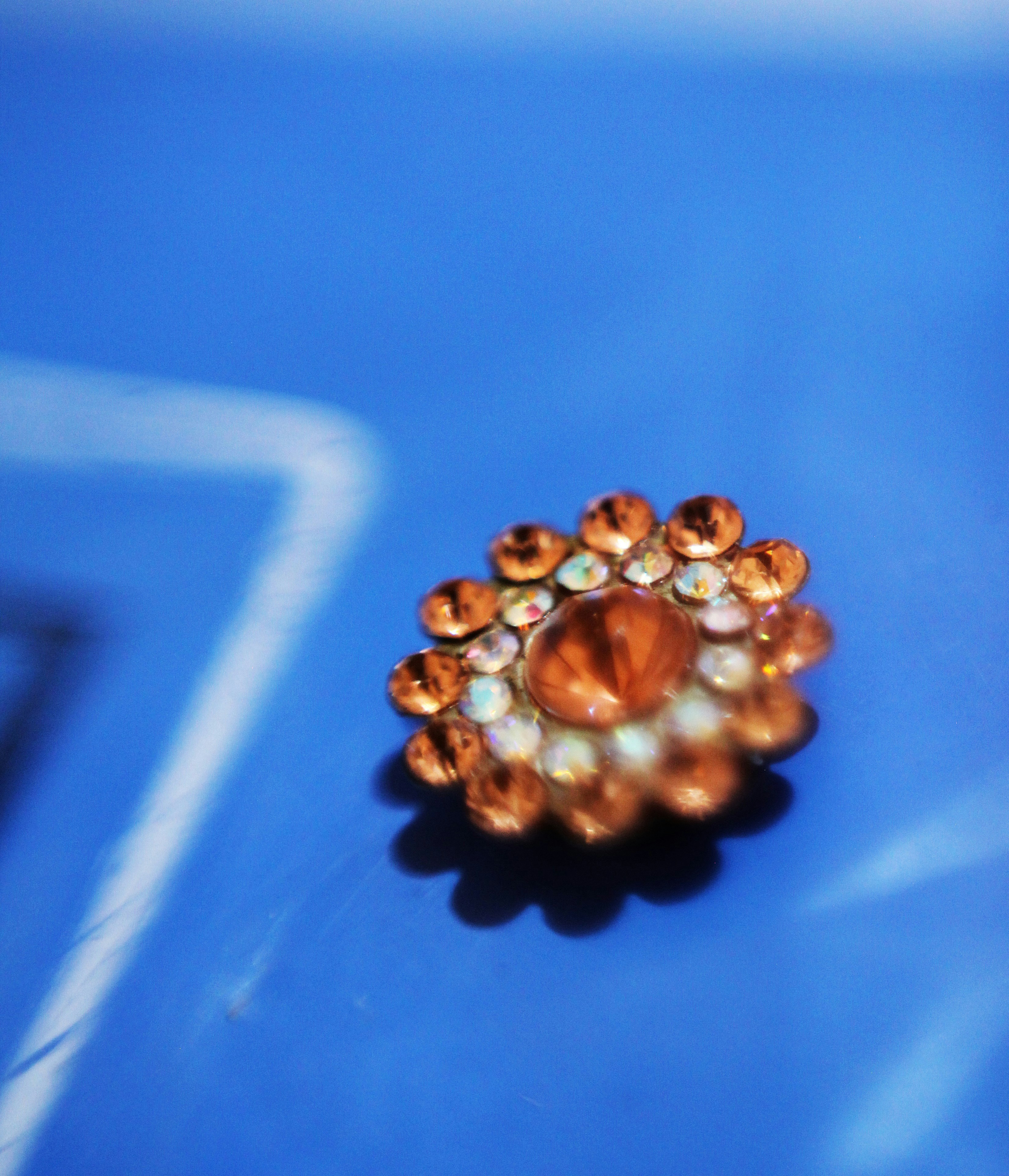 A close up of a brooch on a blue surface