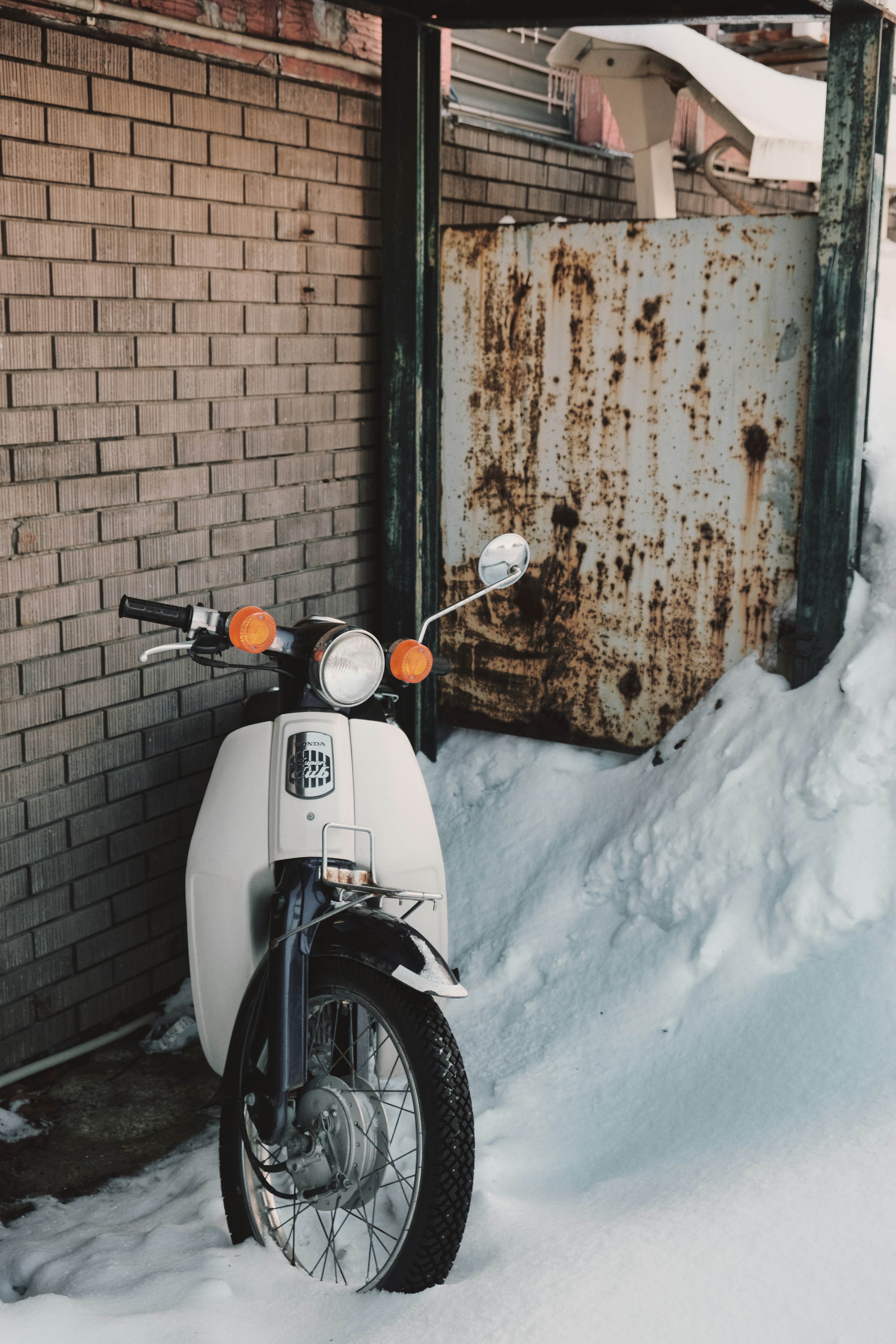 A motorcycle parked in the snow next to a building