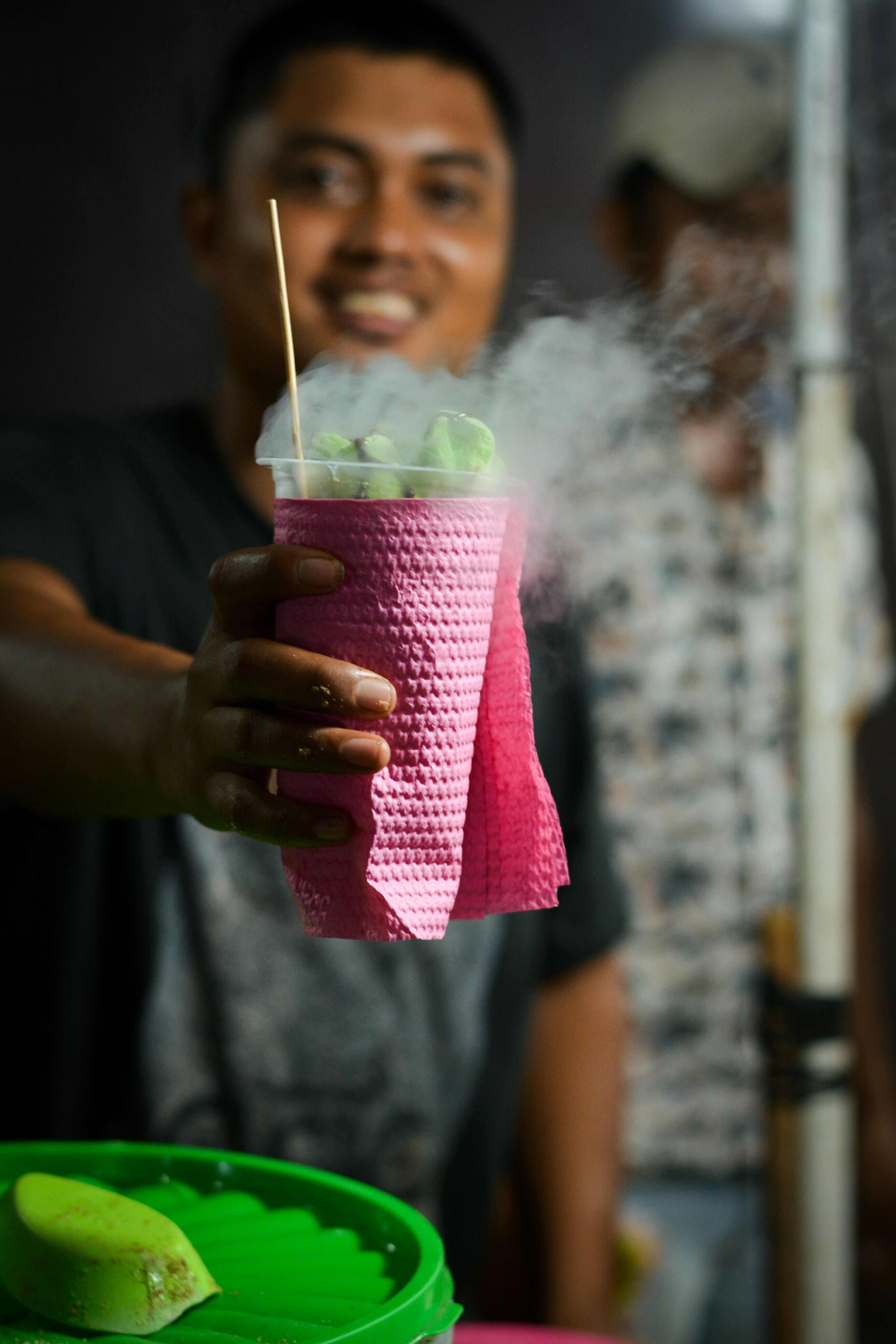 A man holding a pink cup with a straw