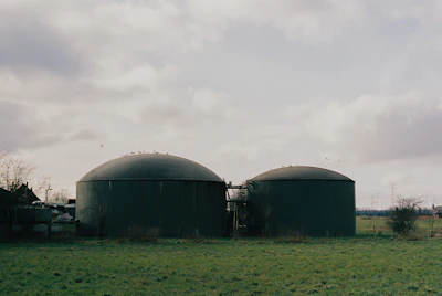 Two biogas digester tanks in a green field