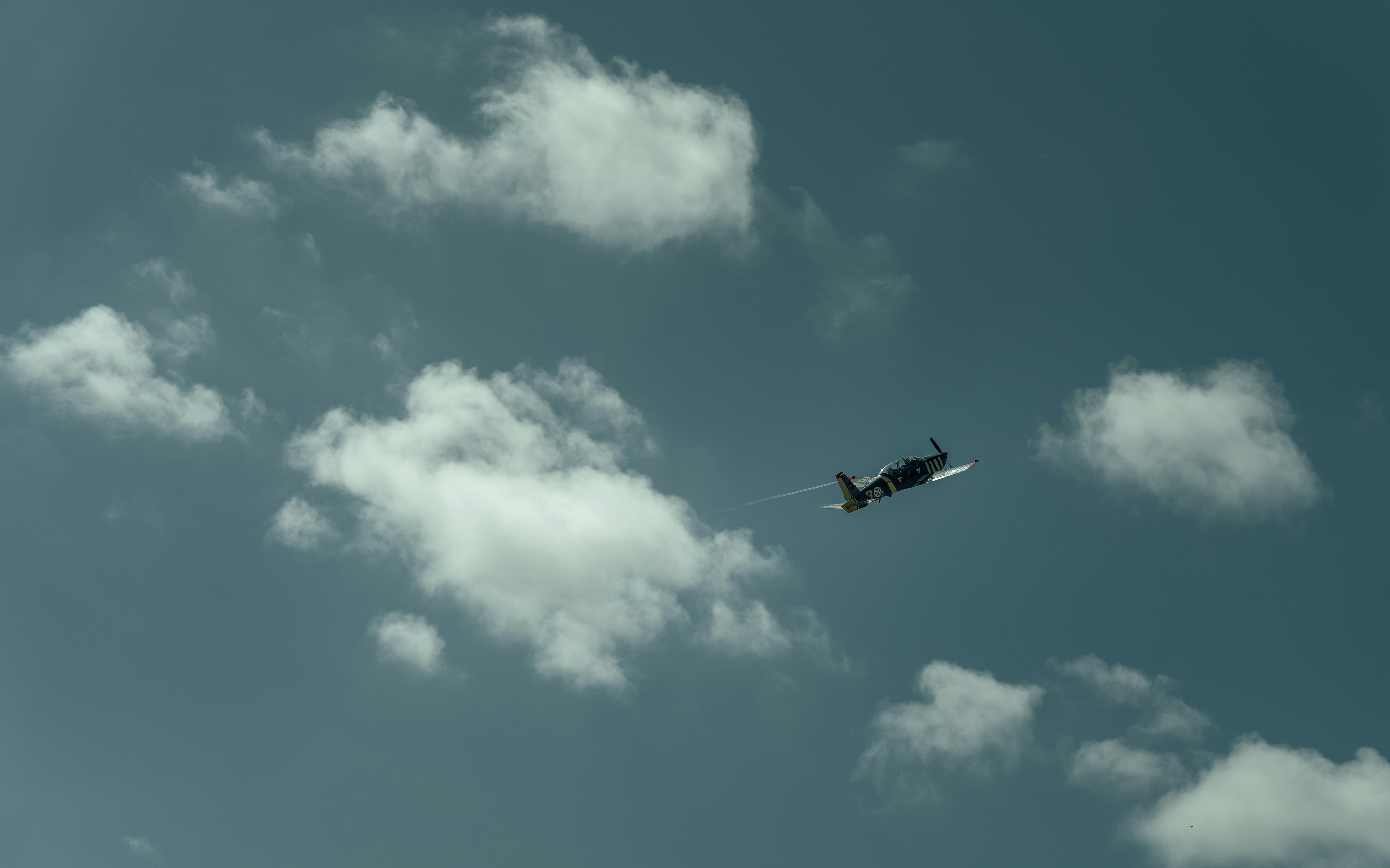 A plane flying through a cloudy blue sky, 