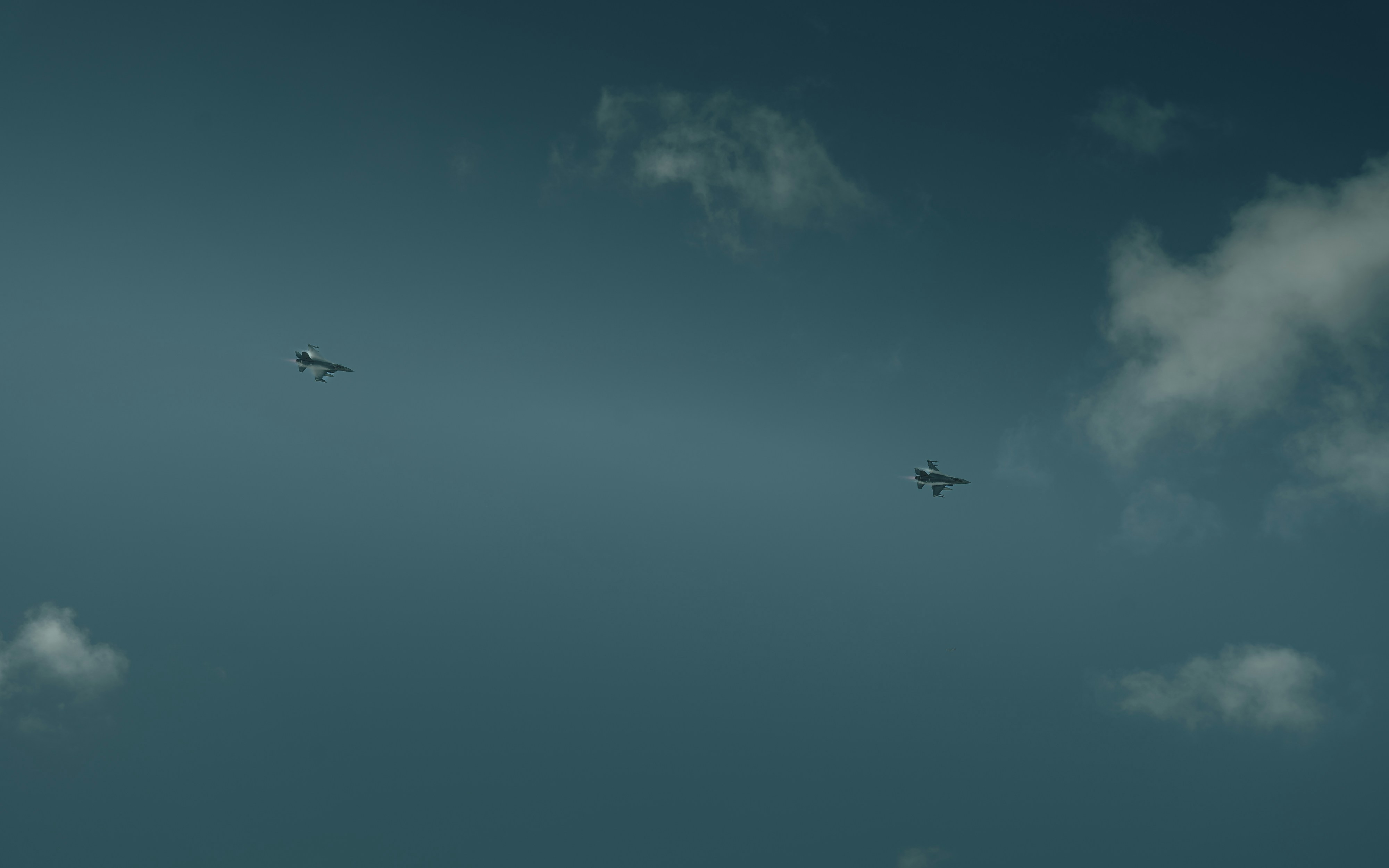A group of airplanes flying through a cloudy blue sky