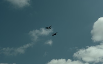 Two airplanes flying in the sky on a cloudy day