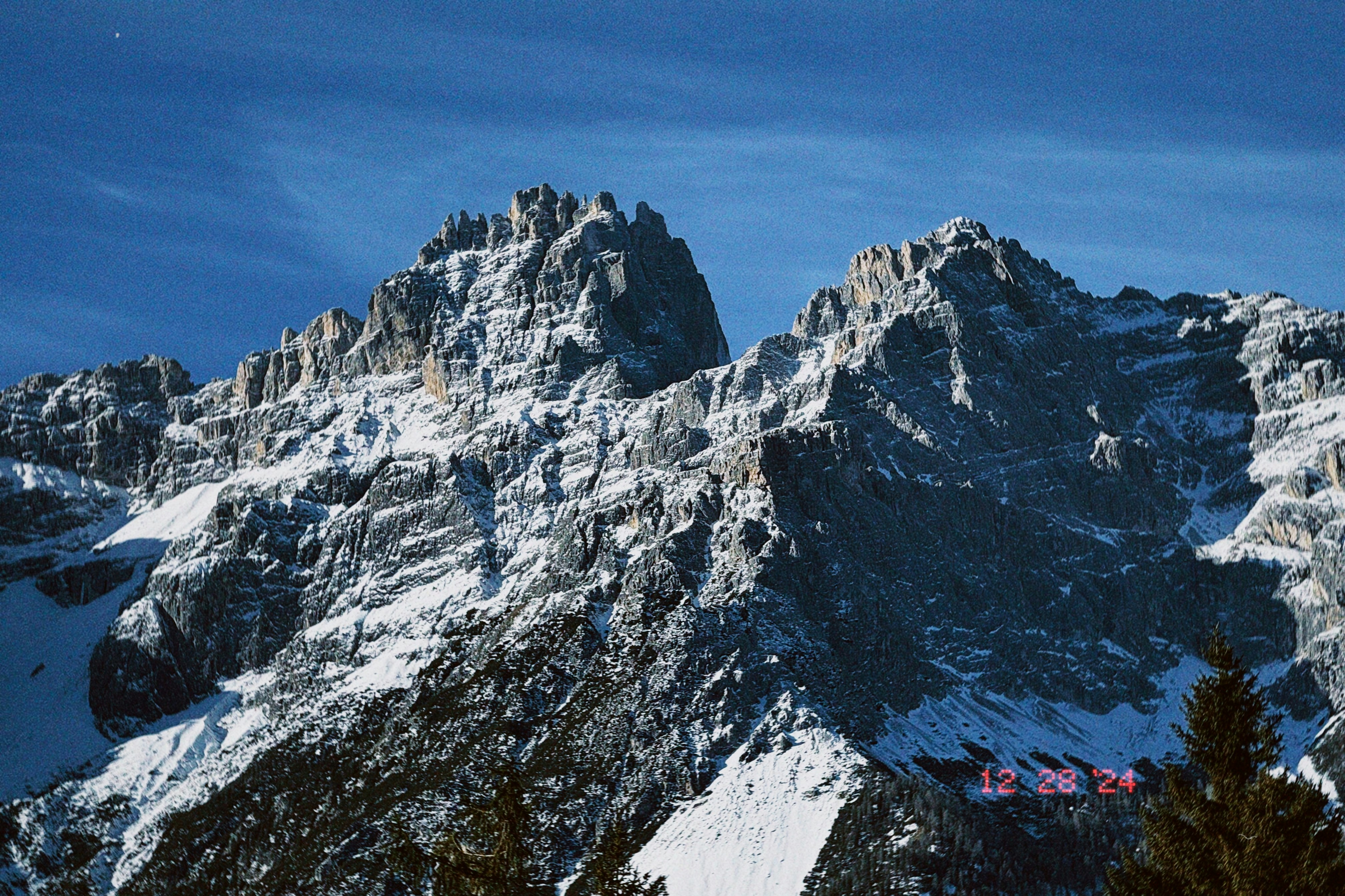 A snow covered mountain with trees in the foreground