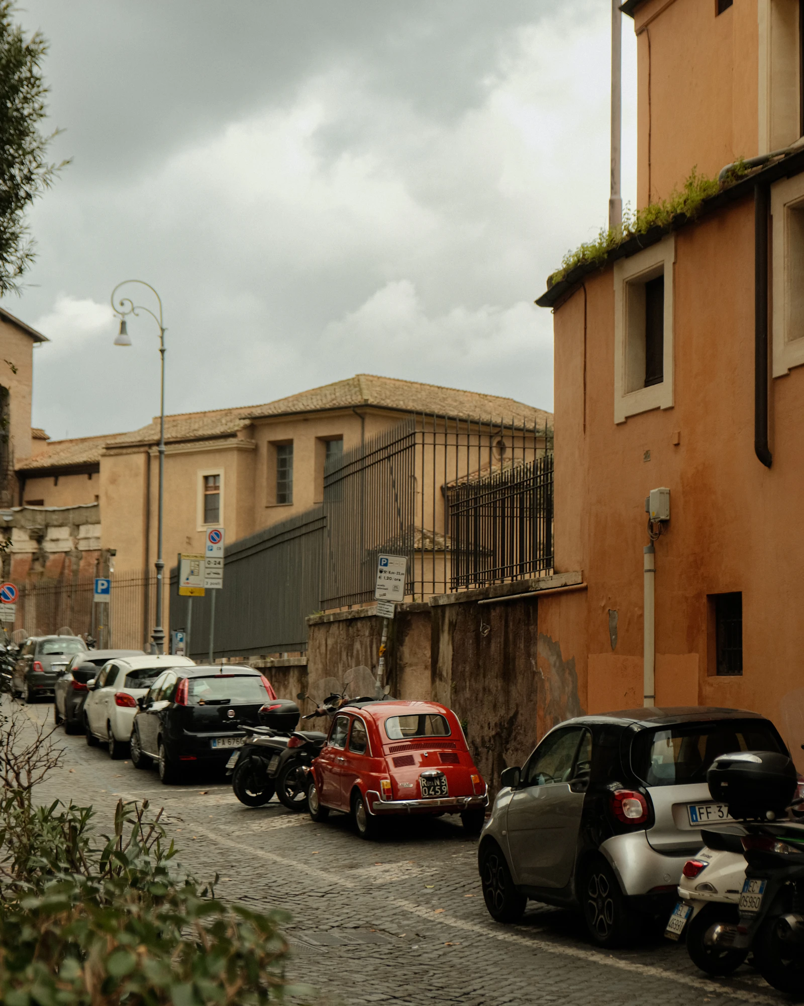 Parked cars along a street between buildings in Rome