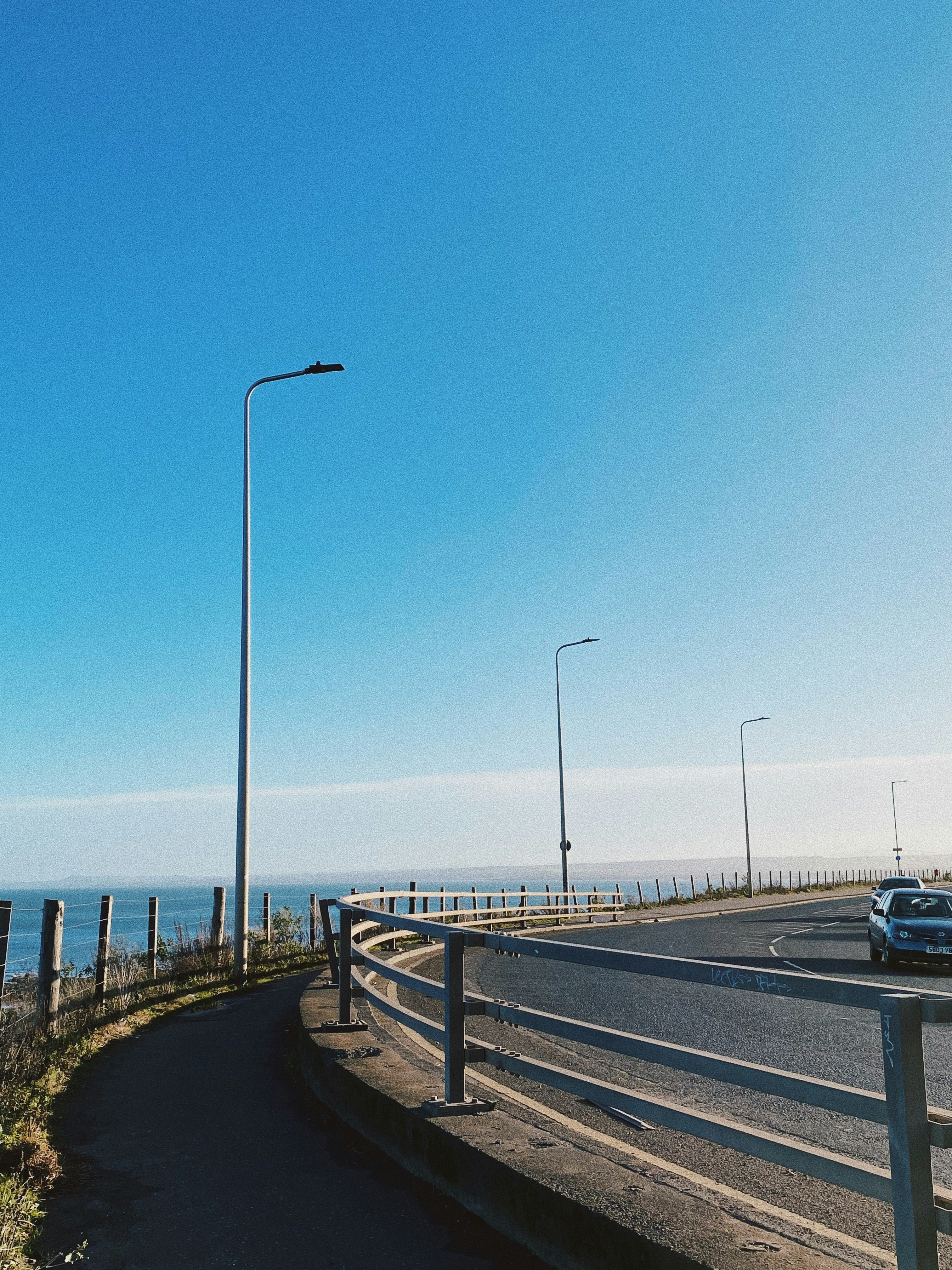 A car driving down a road next to the ocean