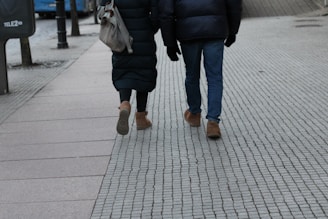 Two people walking down a sidewalk holding umbrellas