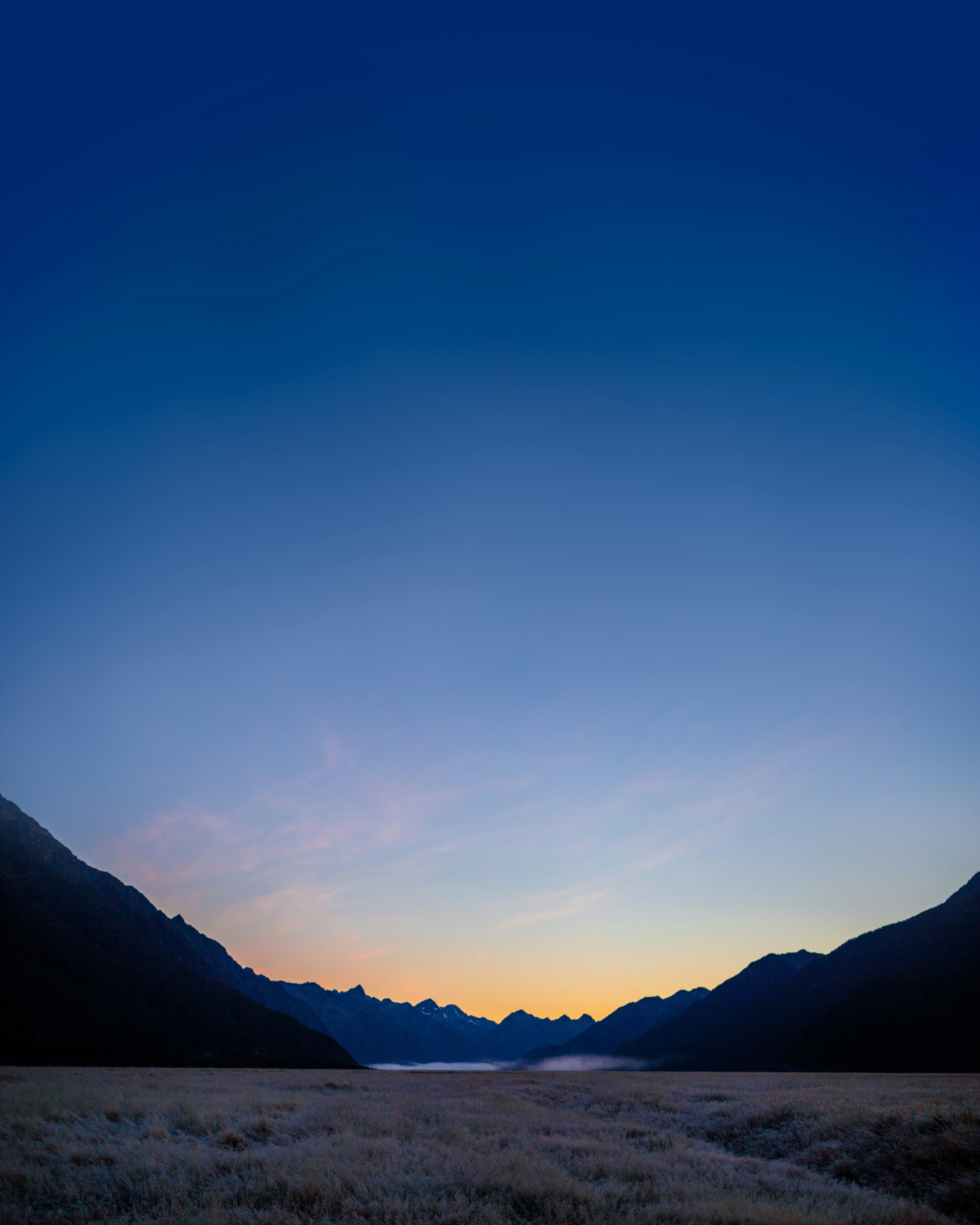A field with mountains and a body of water in the distance
