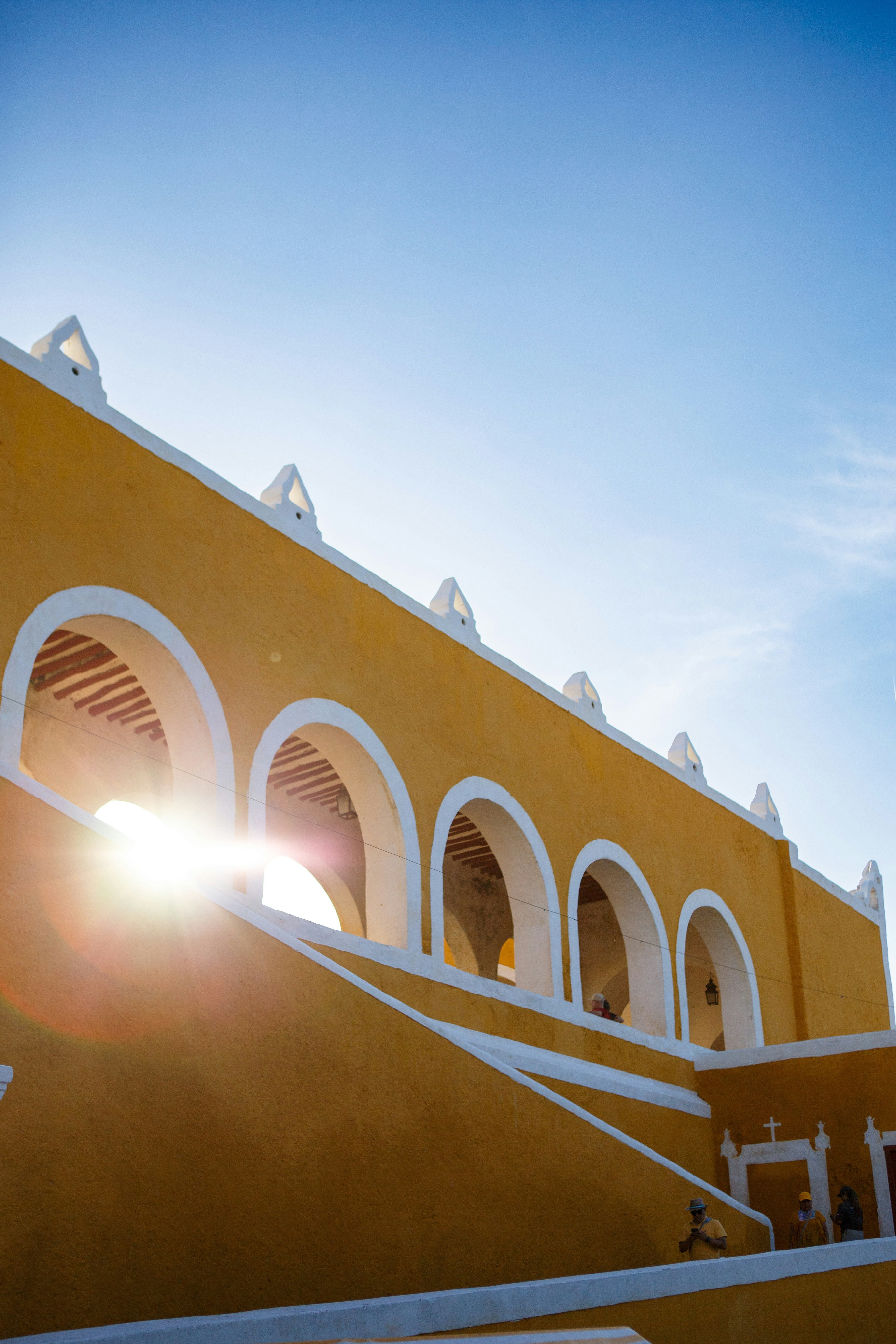 The sun shines brightly through the arches of a building