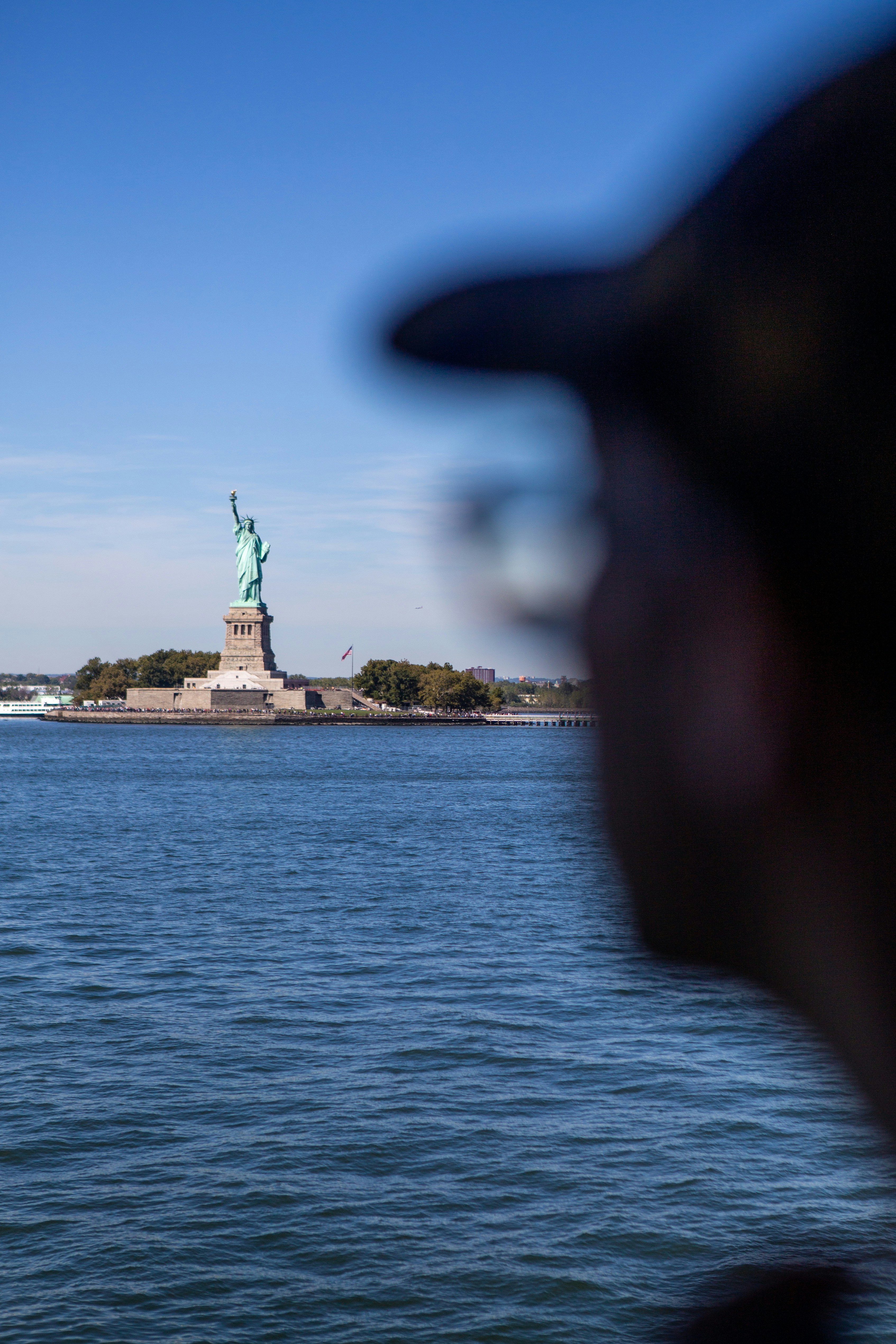 A man looking at the statue of liberty from across the water