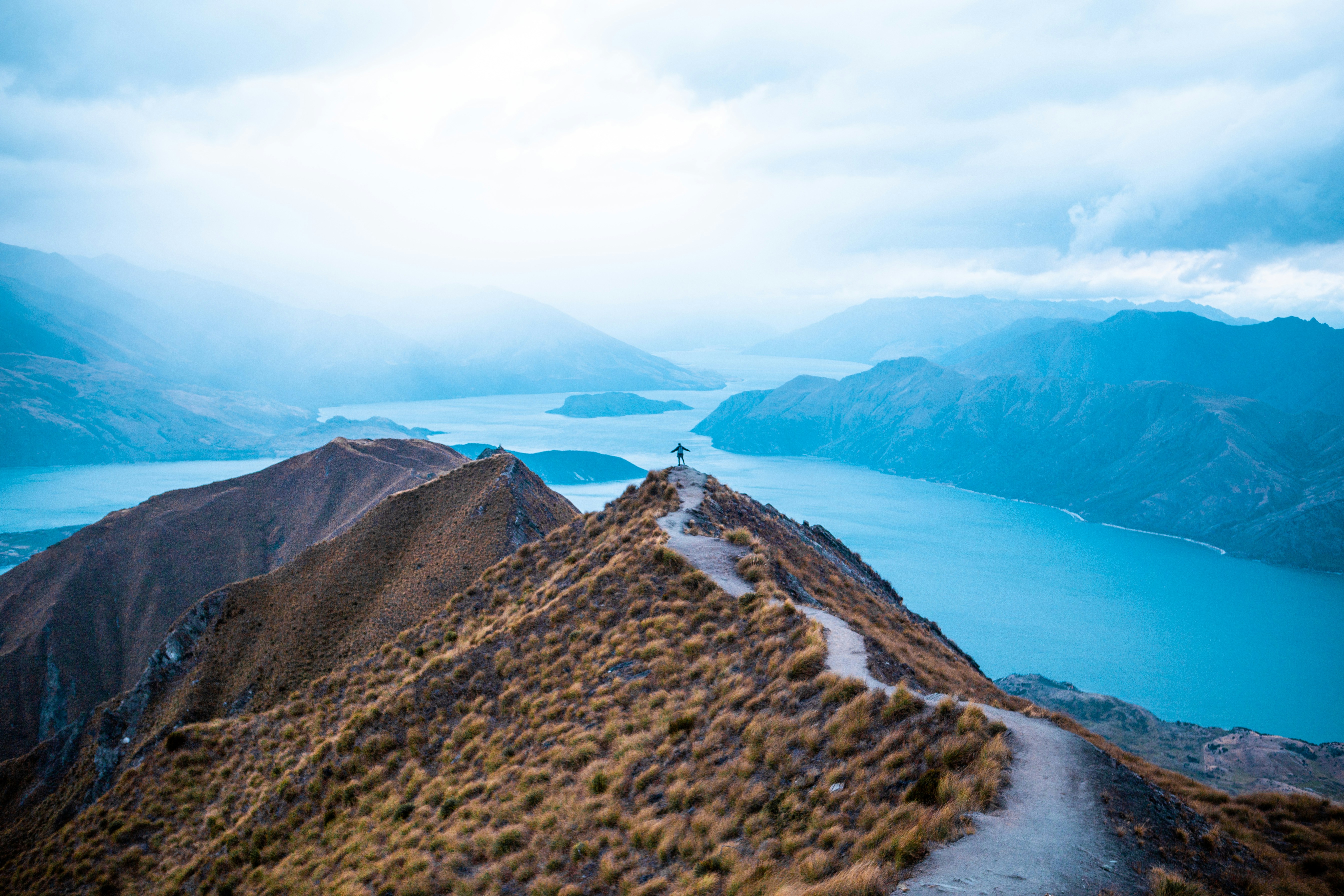 A man standing on top of a mountain next to a lake