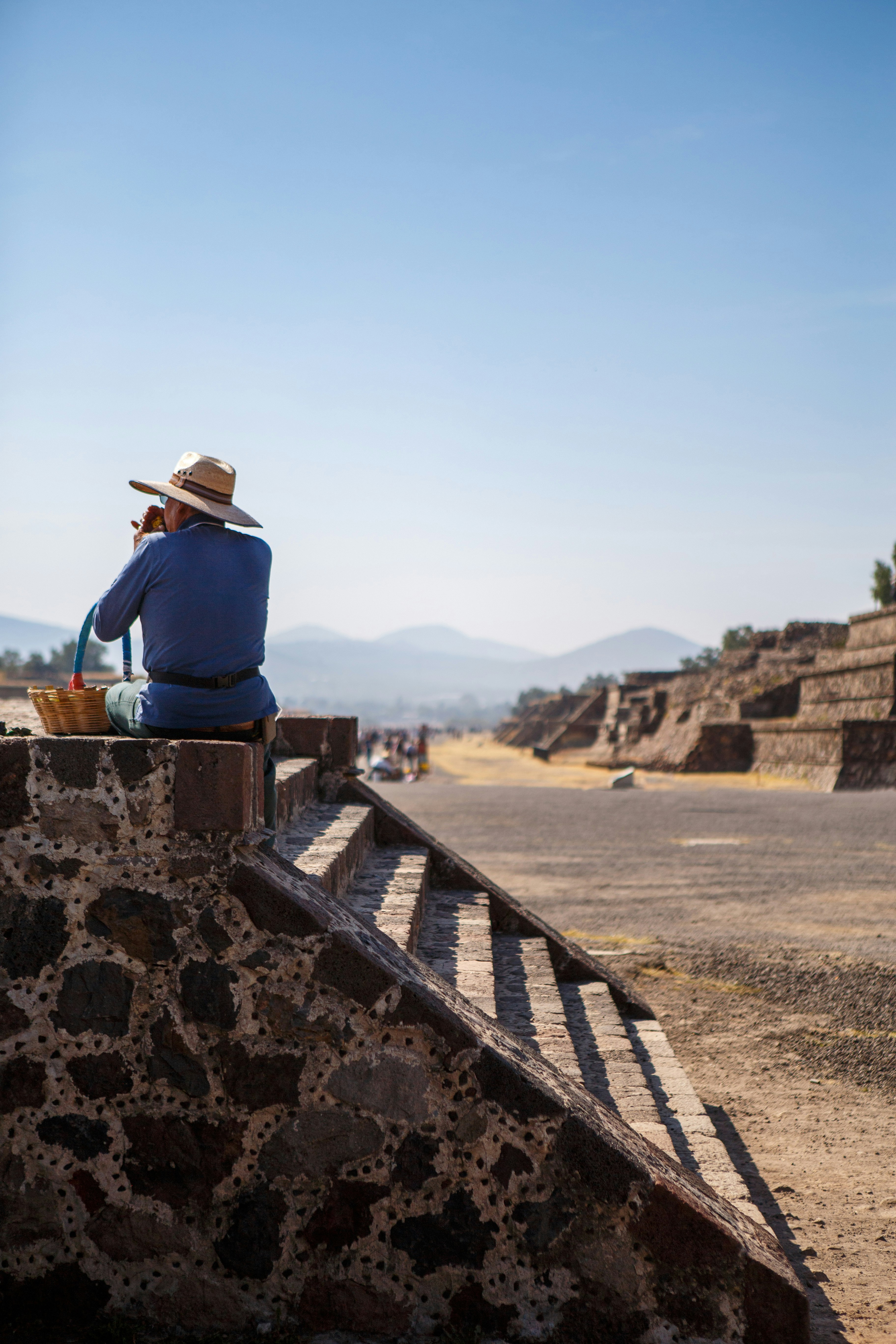 A man in a hat sitting on top of a stone structure