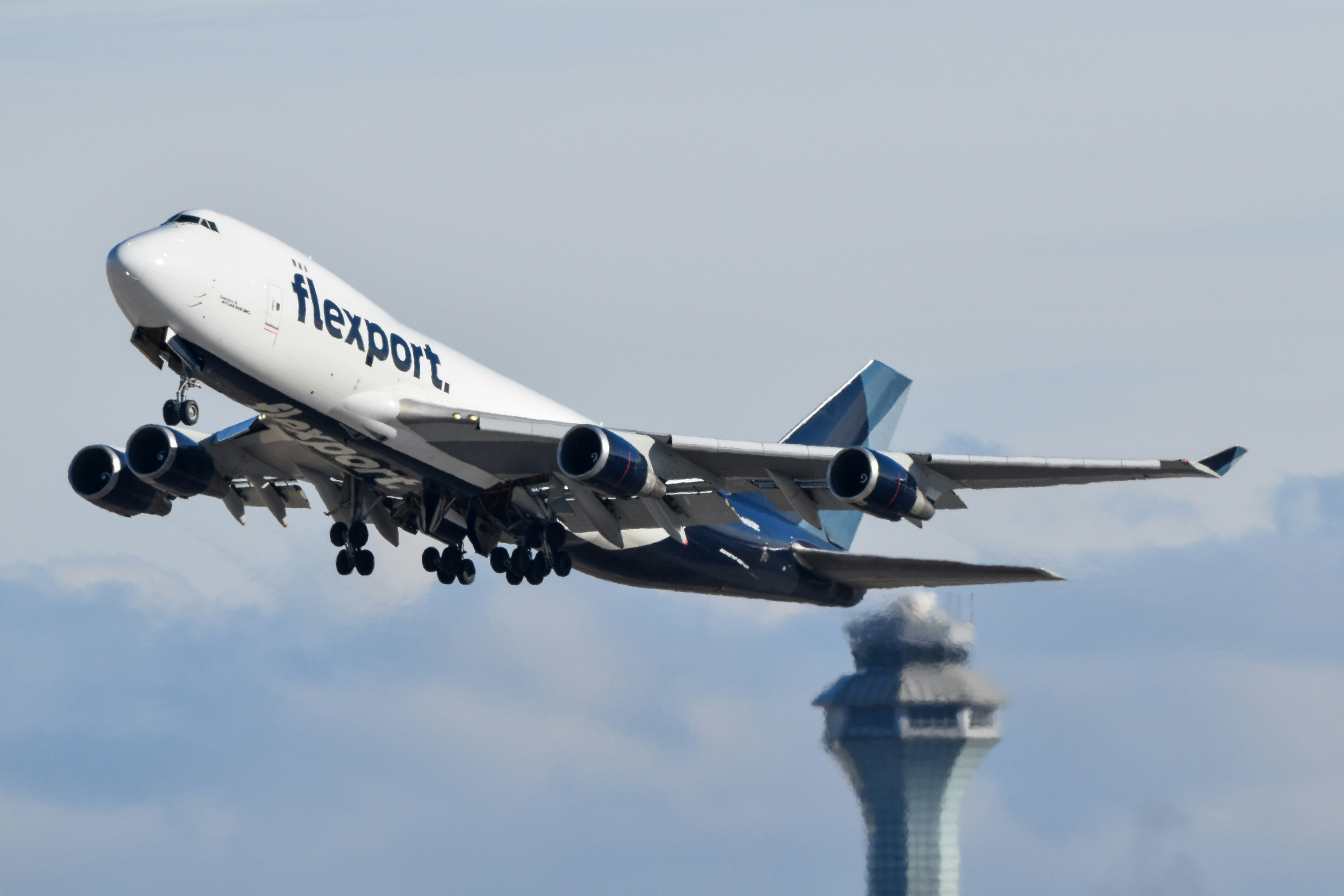 A large jetliner flying through a cloudy blue sky, Flexport 747 departing Chicago O