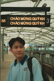 A man standing in front of a sign at an airport