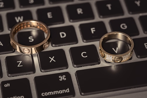 Two wedding rings sitting on top of a laptop keyboard