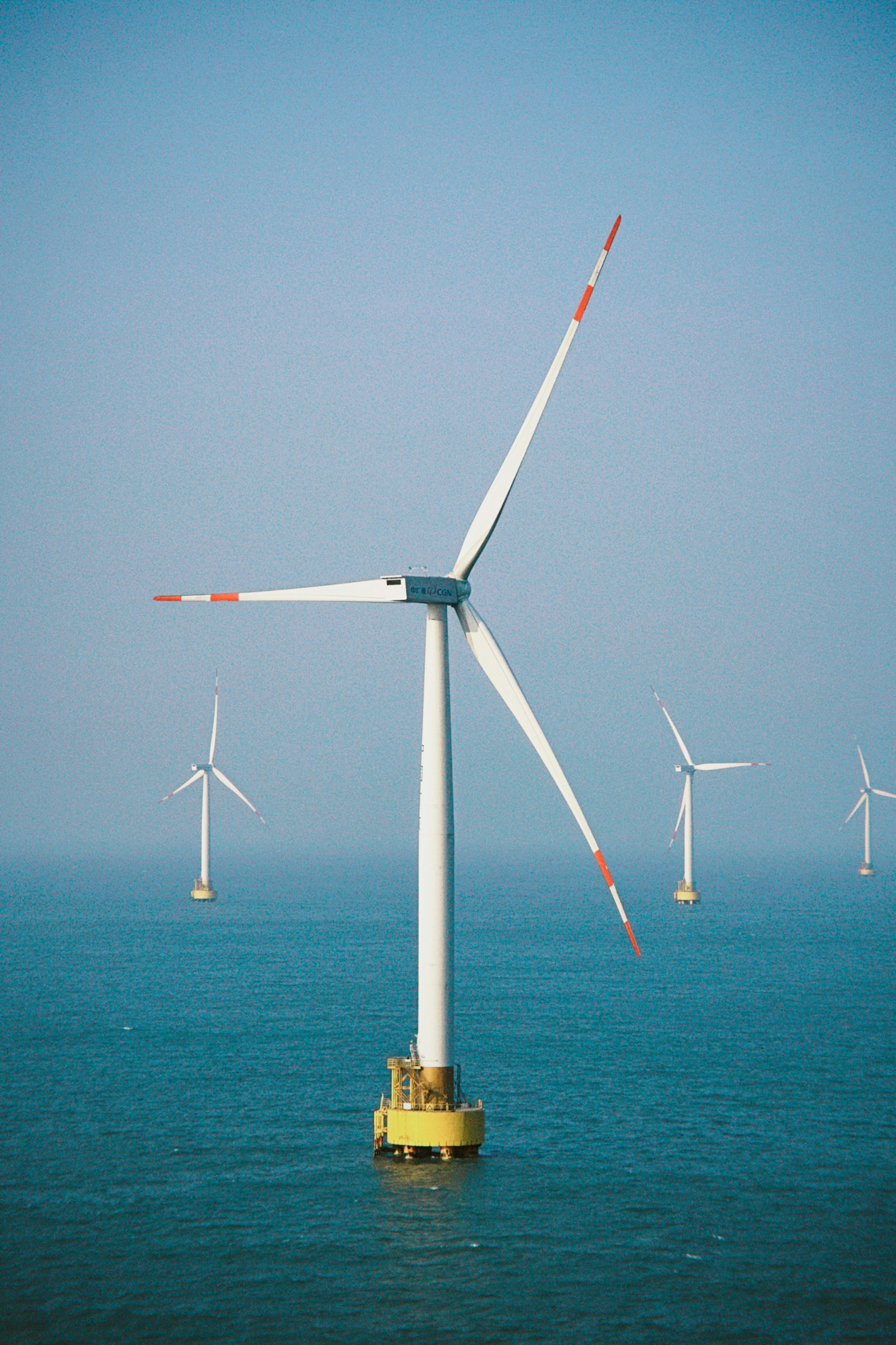 A group of windmills floating on top of a body of water