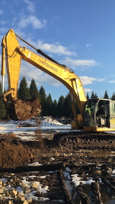 A large yellow excavator sitting on top of a pile of dirt