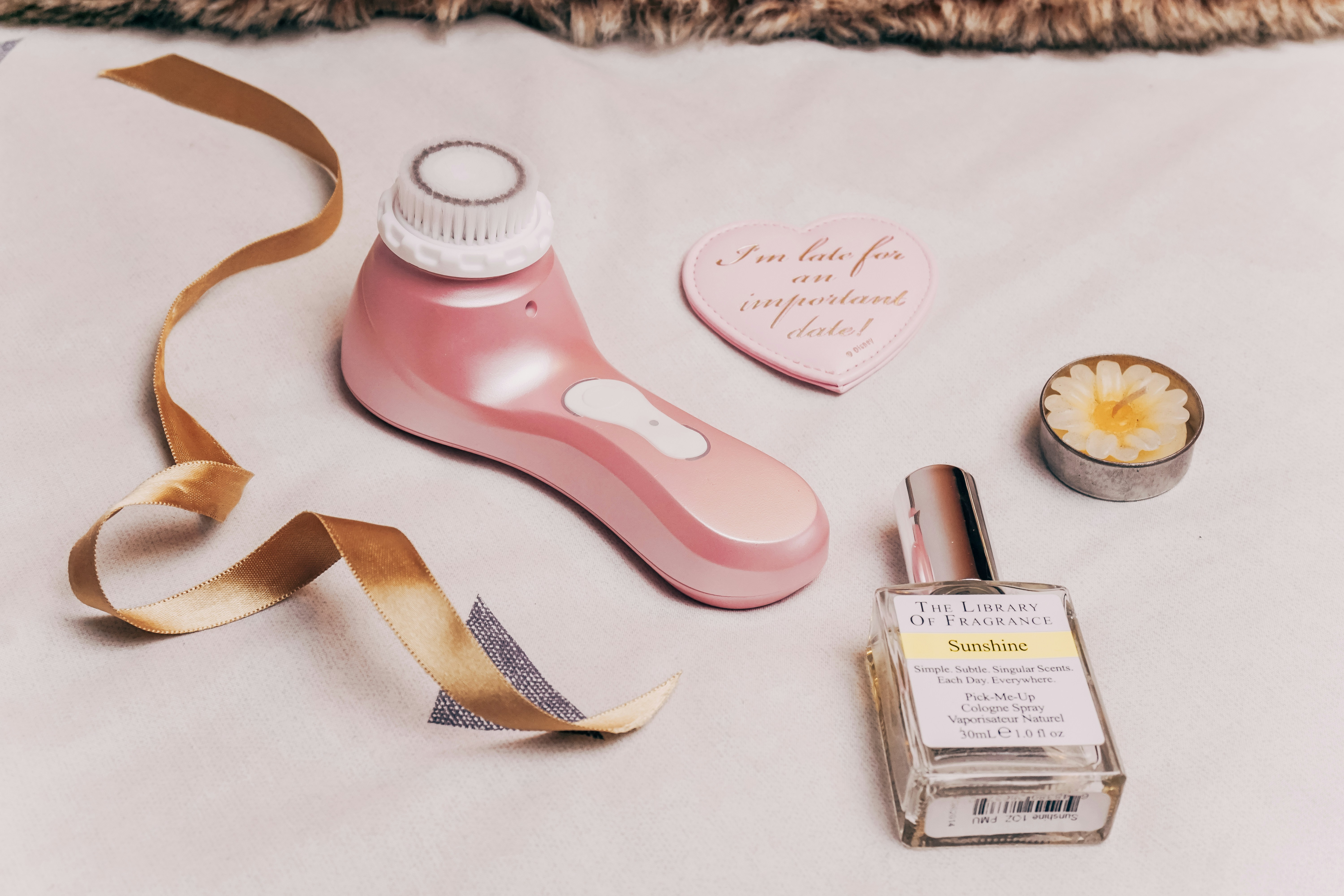 A bottle of perfume, a roll of ribbon, and some other items on a