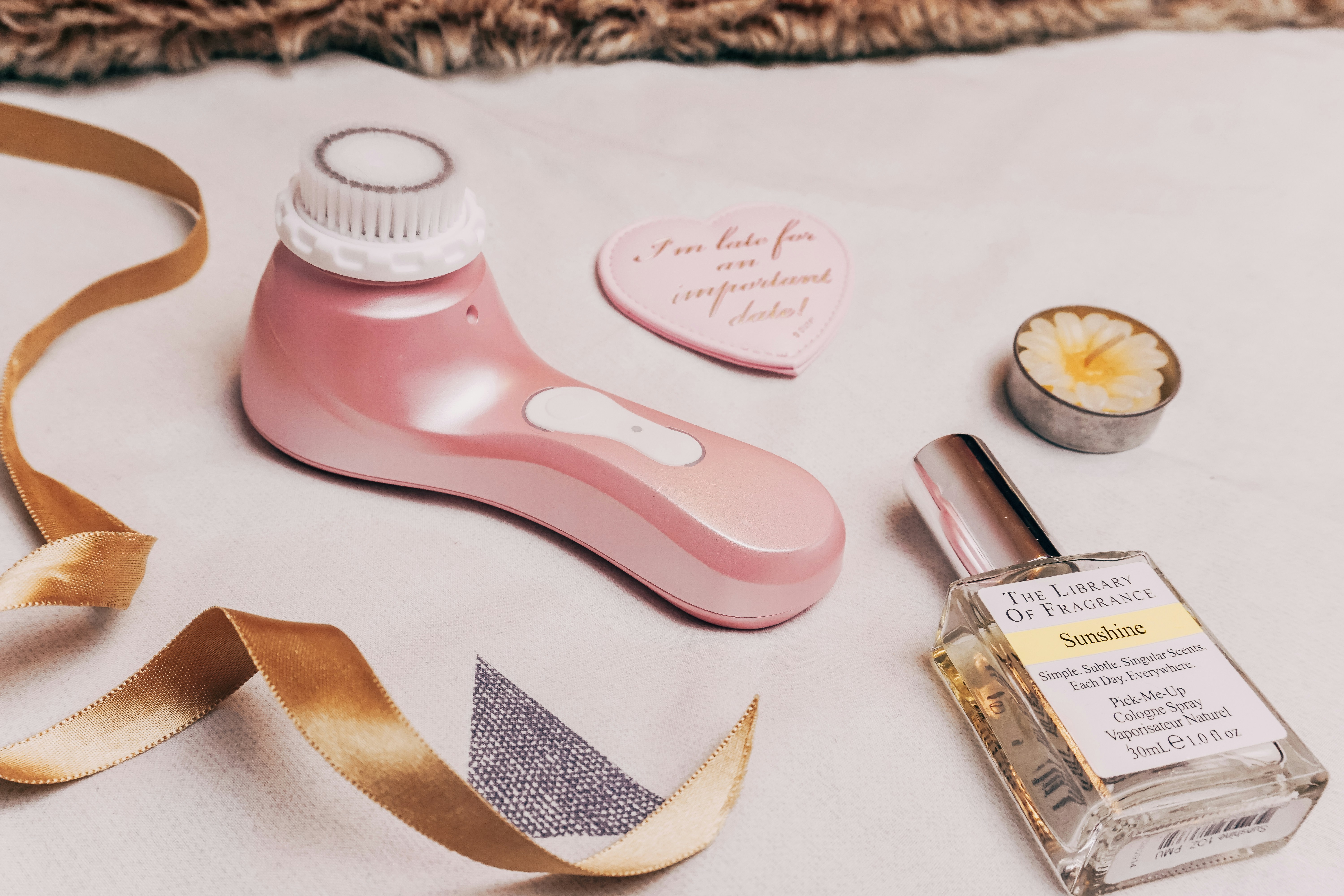 A table topped with a bottle of perfume and a ribbon