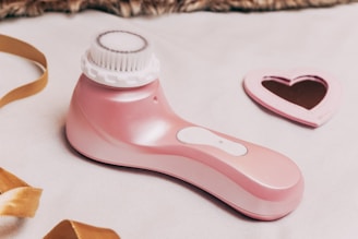 A pink hair dryer sitting on top of a bed