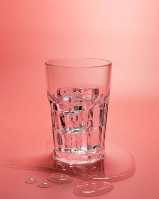 A glass of water on a pink background
