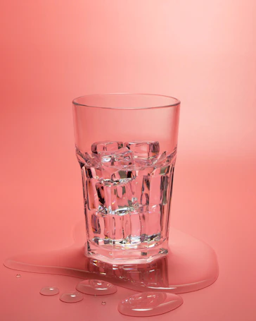 A glass of water on a pink background