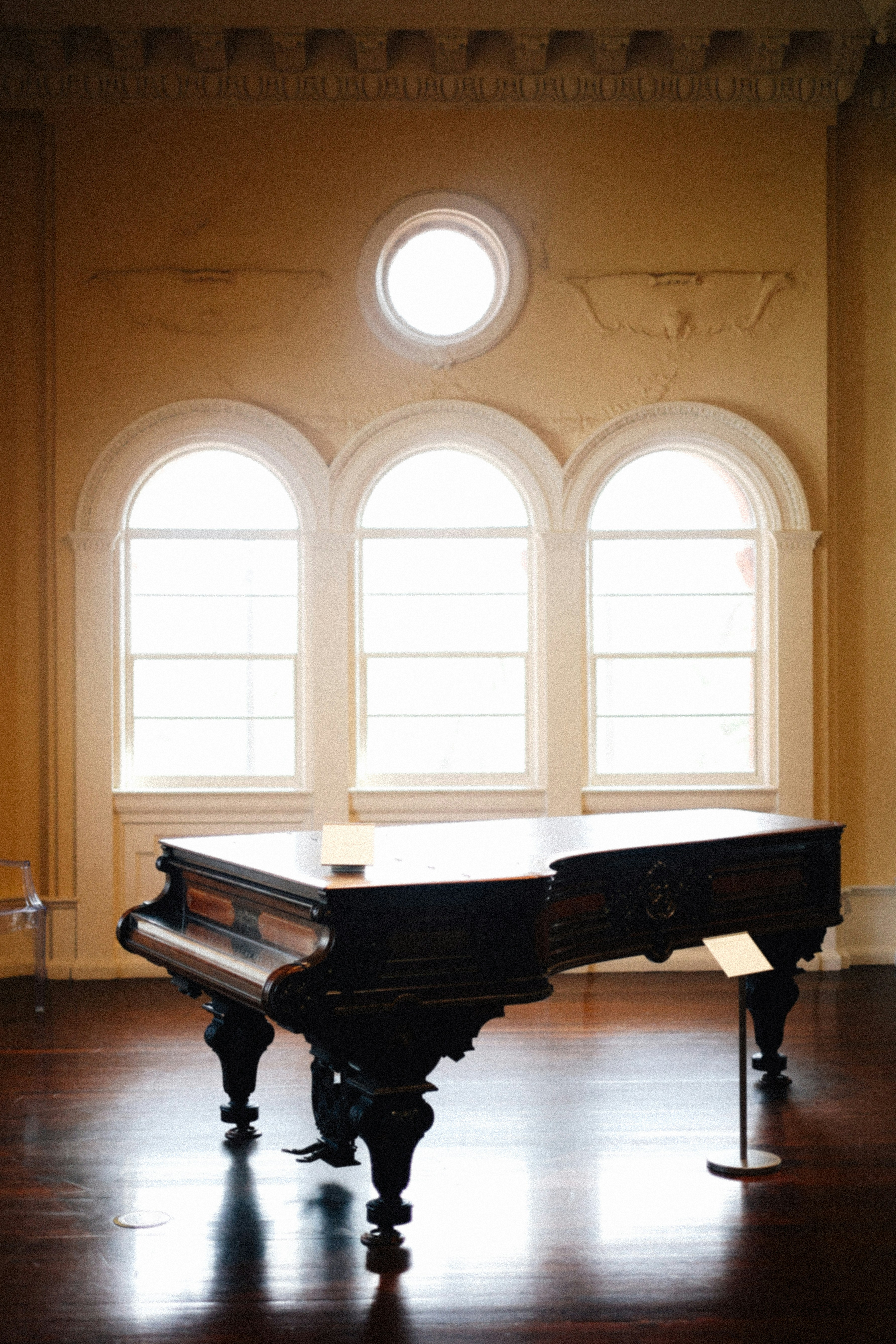 A grand piano in a large room with arched windows