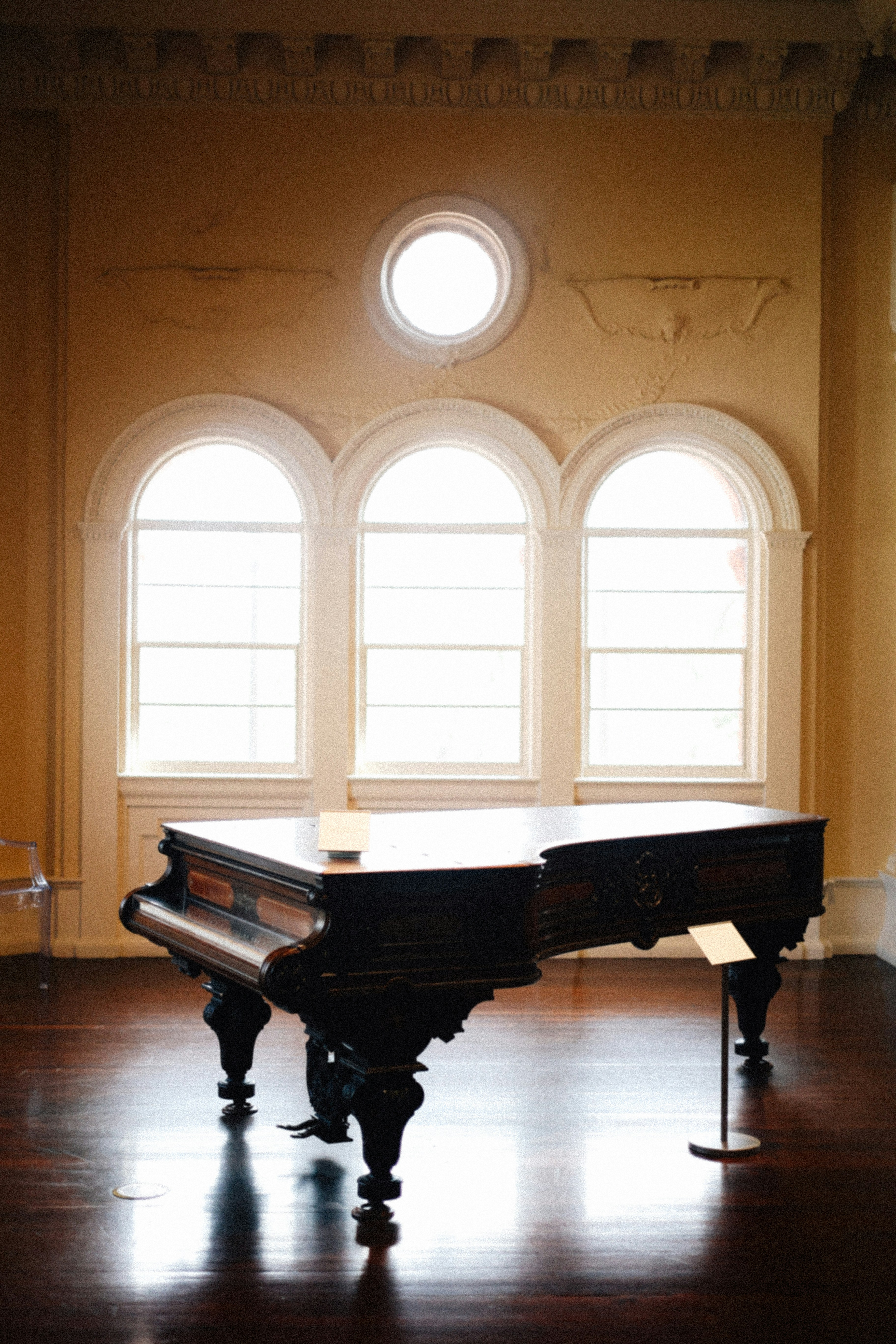 A grand piano in a large room with arched windows