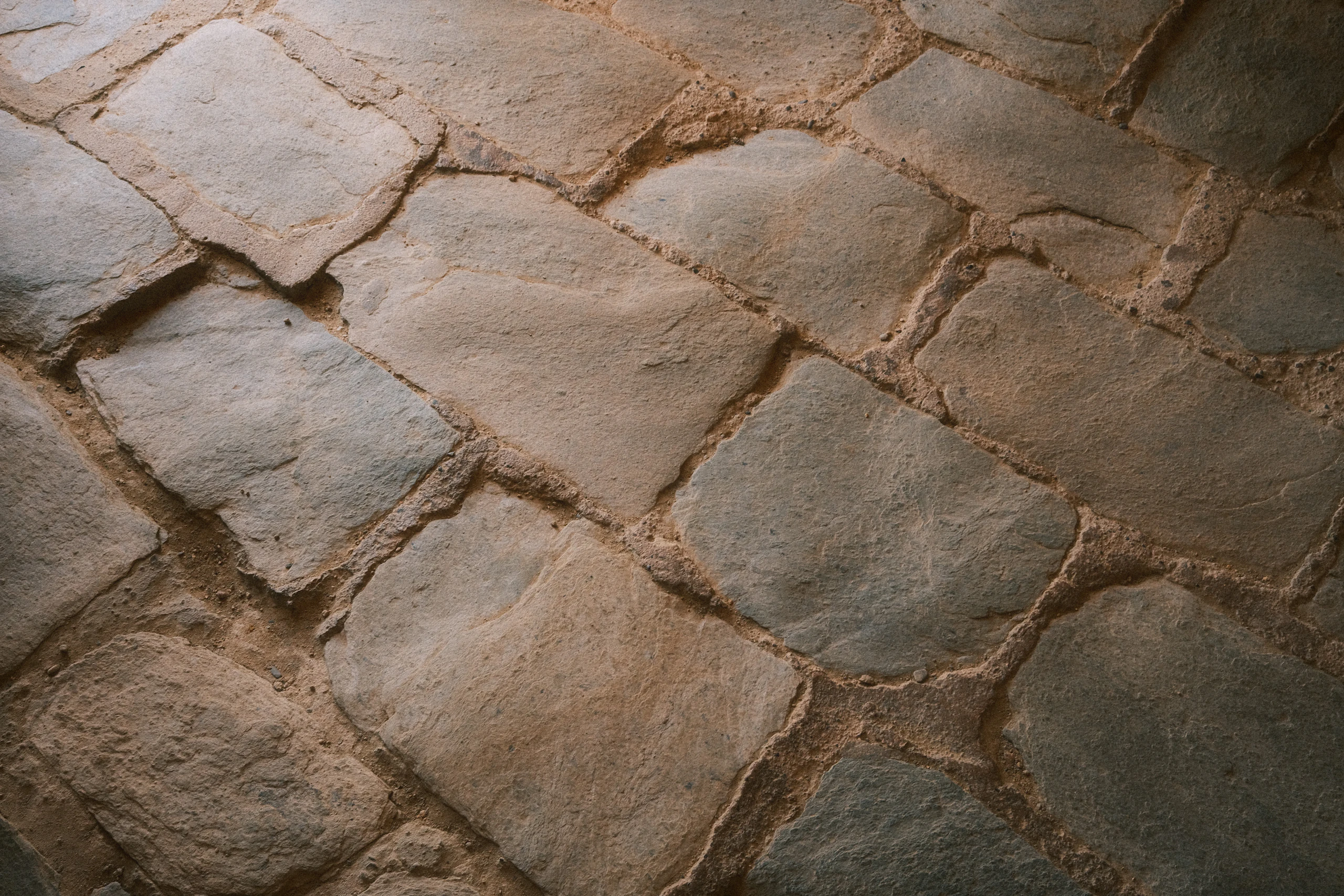 Tumbled limestone paving, its joints filled with fine sand.