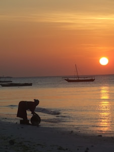 The sun is setting over the ocean with boats in the water