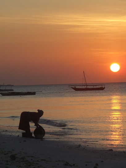 The sun is setting over the ocean with boats in the water