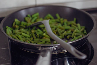 A pan filled with green beans on top of a stove