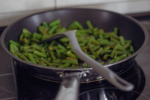 A pan filled with green beans on top of a stove
