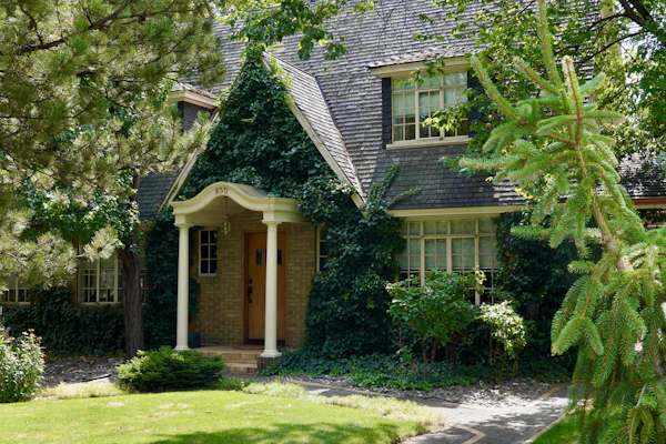 House with a green lawn and trees in front