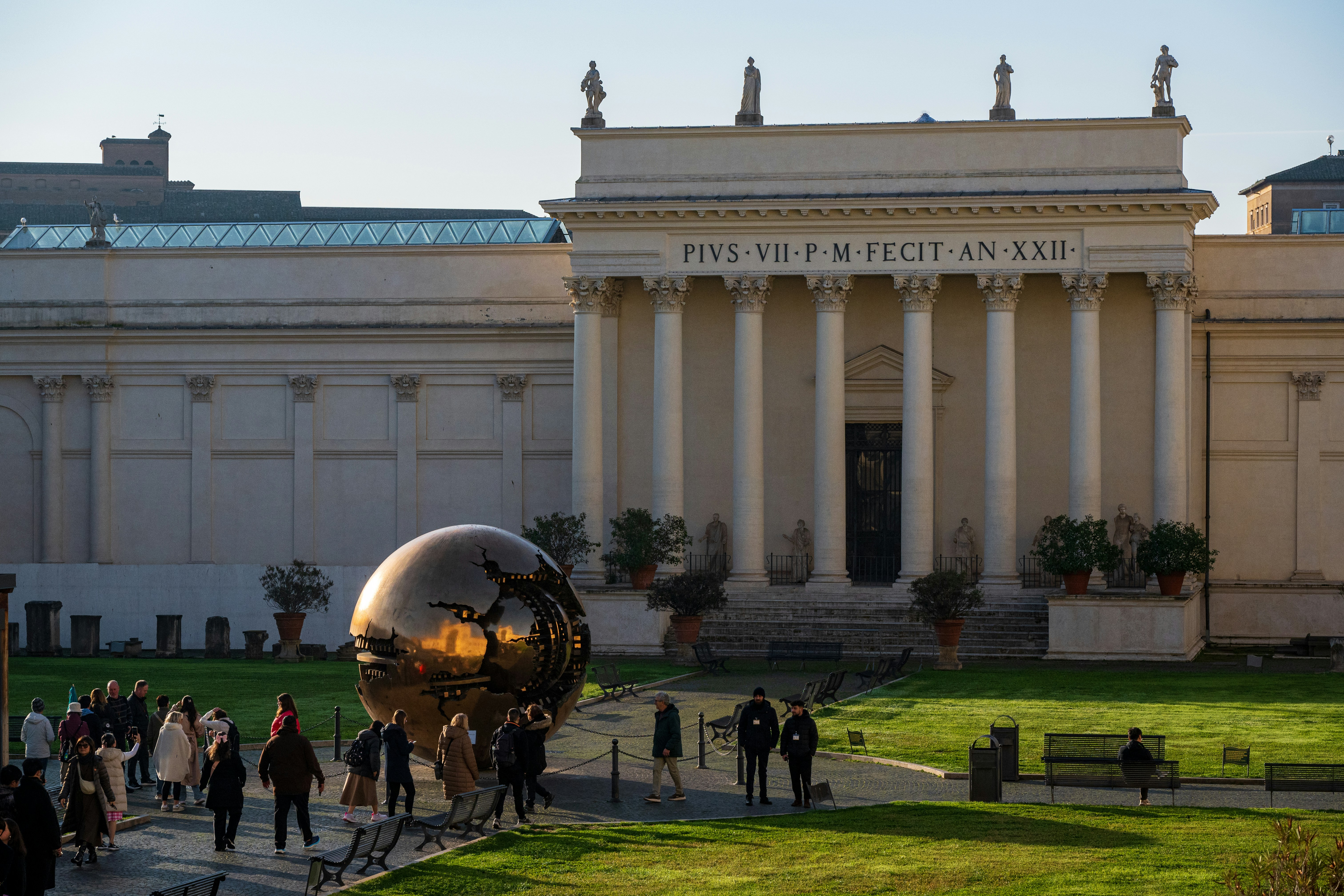 A wide-angle view of a city museum with visitors moving across the plaza under shifting daylight.