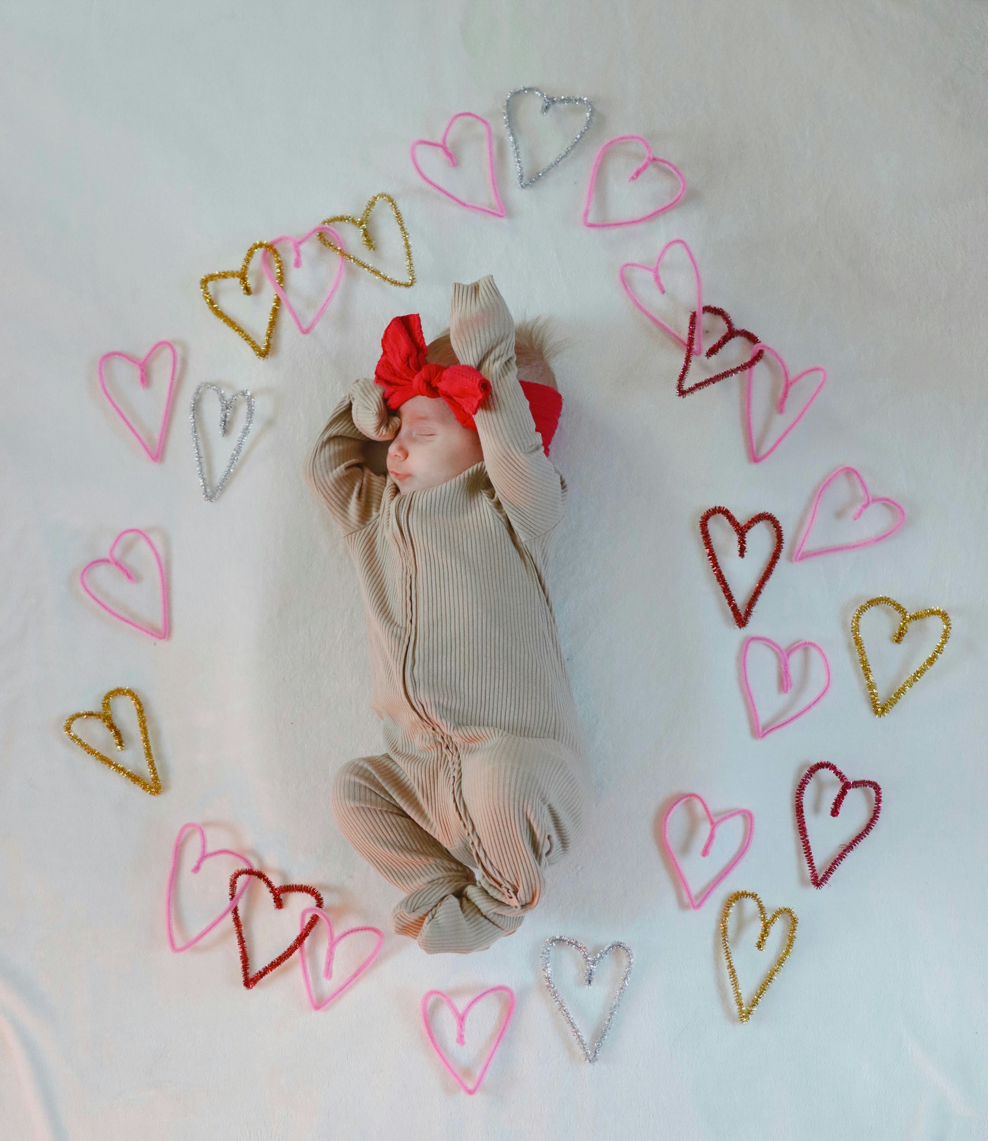 A baby is laying on a blanket with hearts around it