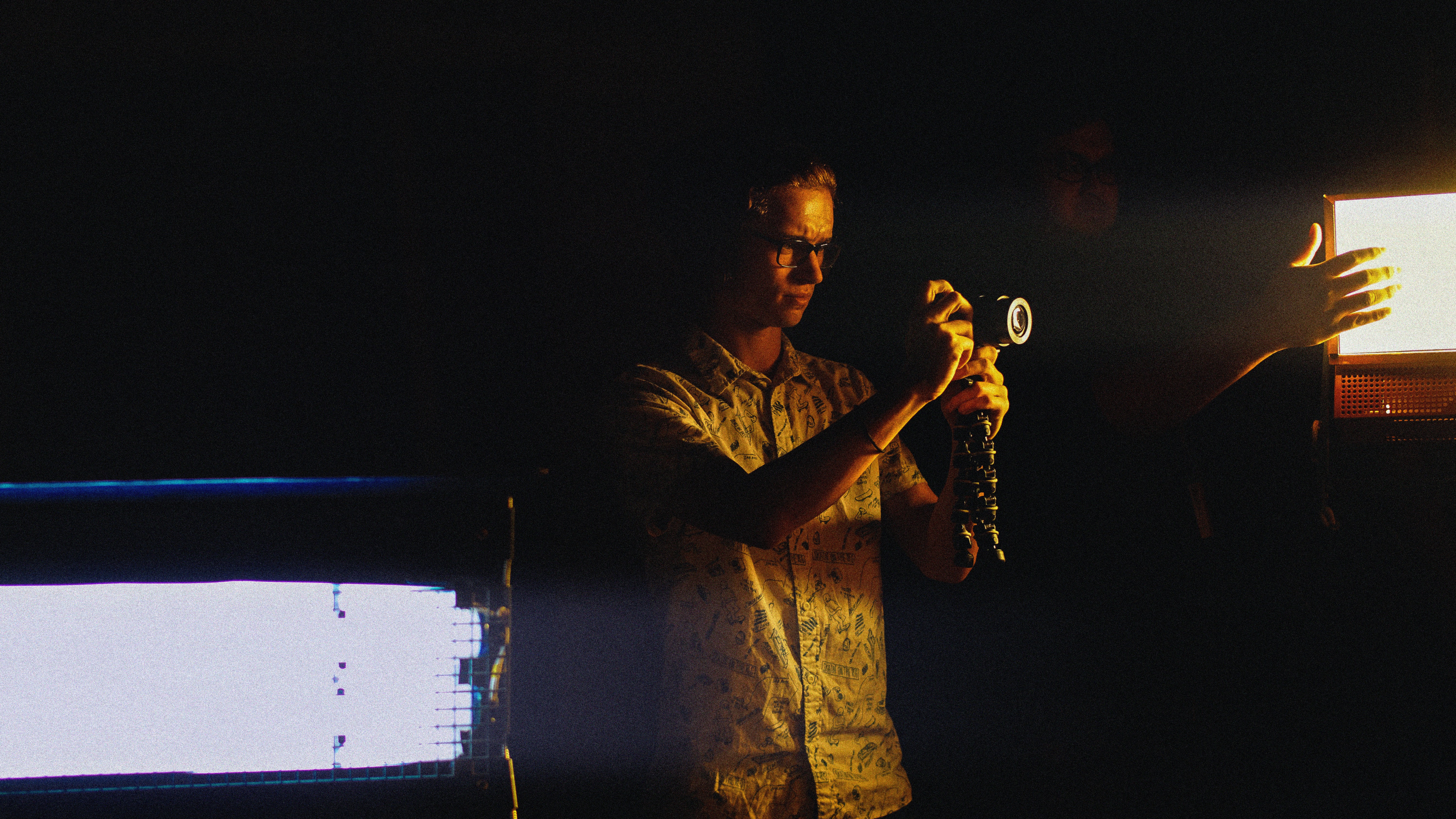 A man holding a camera in a dark room
