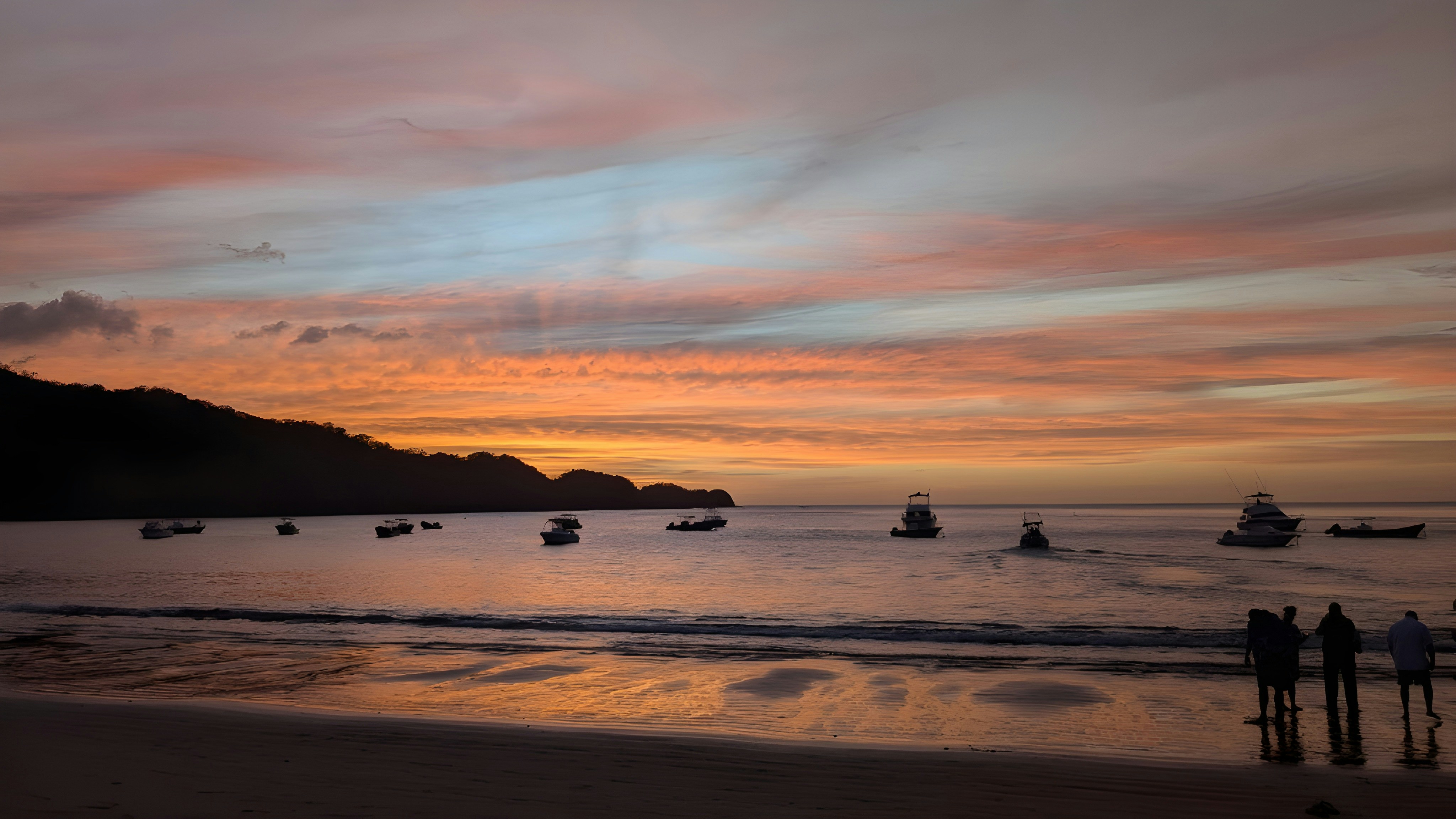 A group of people standing on top of a beach next to the ocean