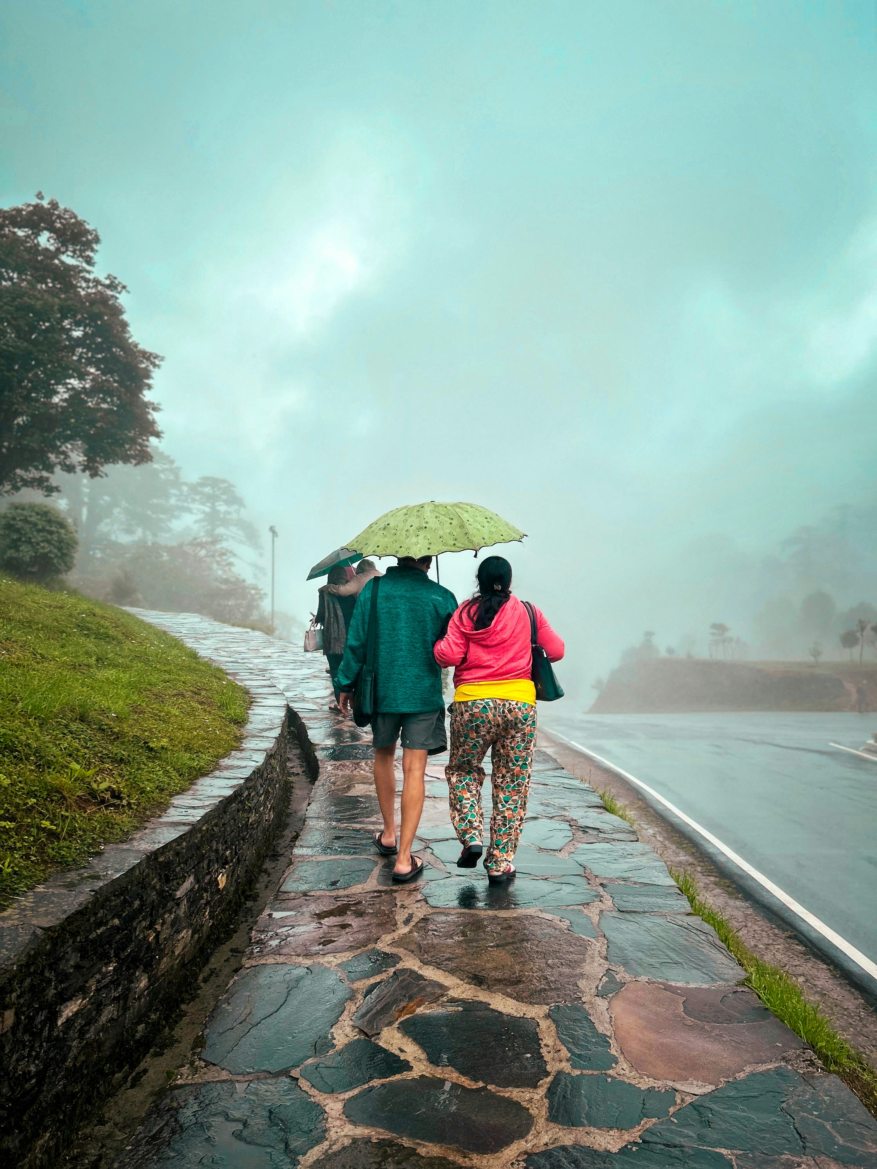 A group of people walking down a rain soaked road