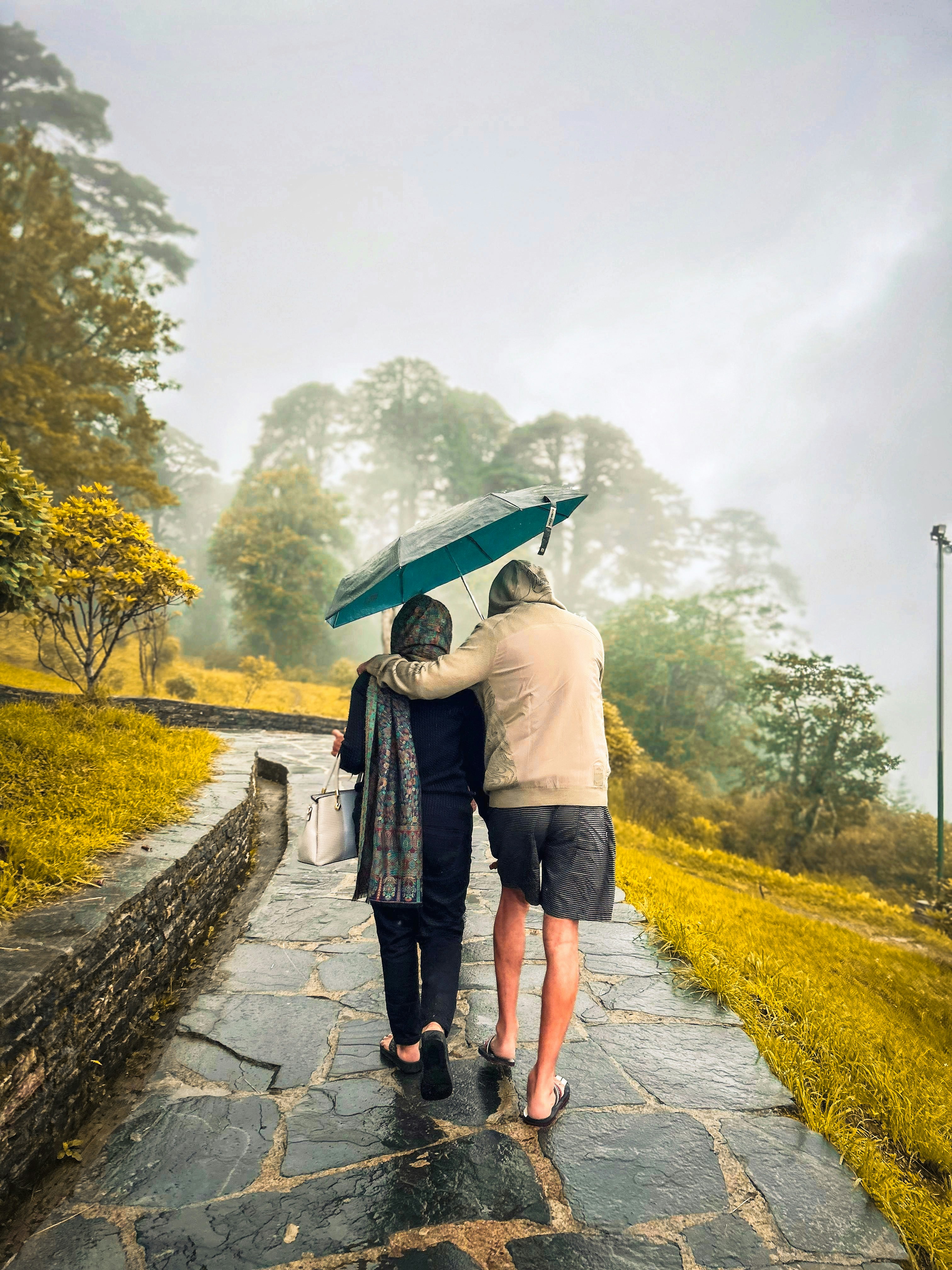 Two people walking down a path holding an umbrella