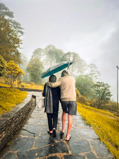 Two people walking down a path holding an umbrella