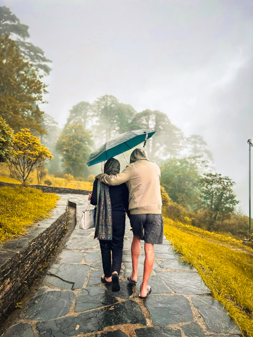 Two people walking down a path holding an umbrella