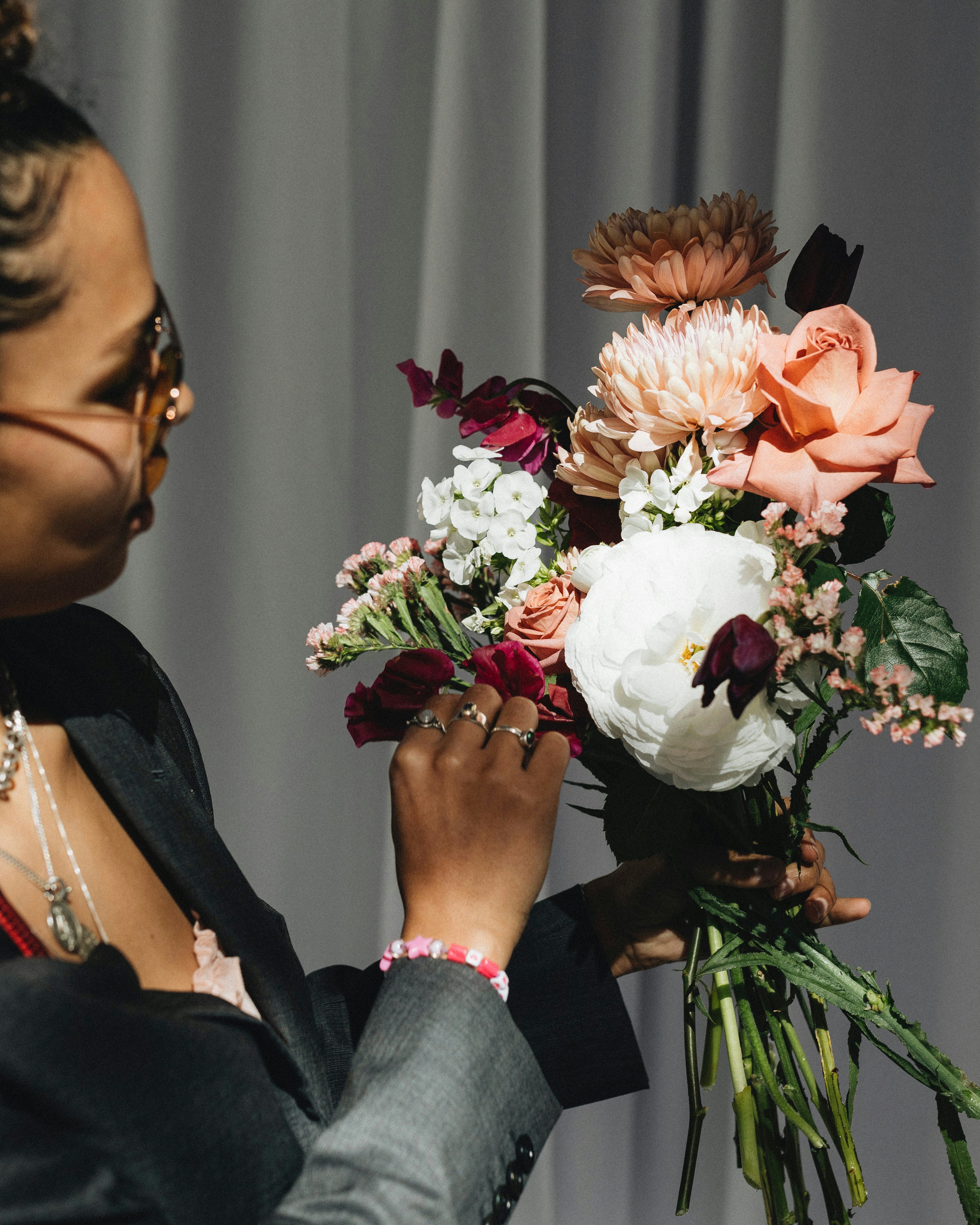 A woman holding a bouquet of flowers in front of a curtain