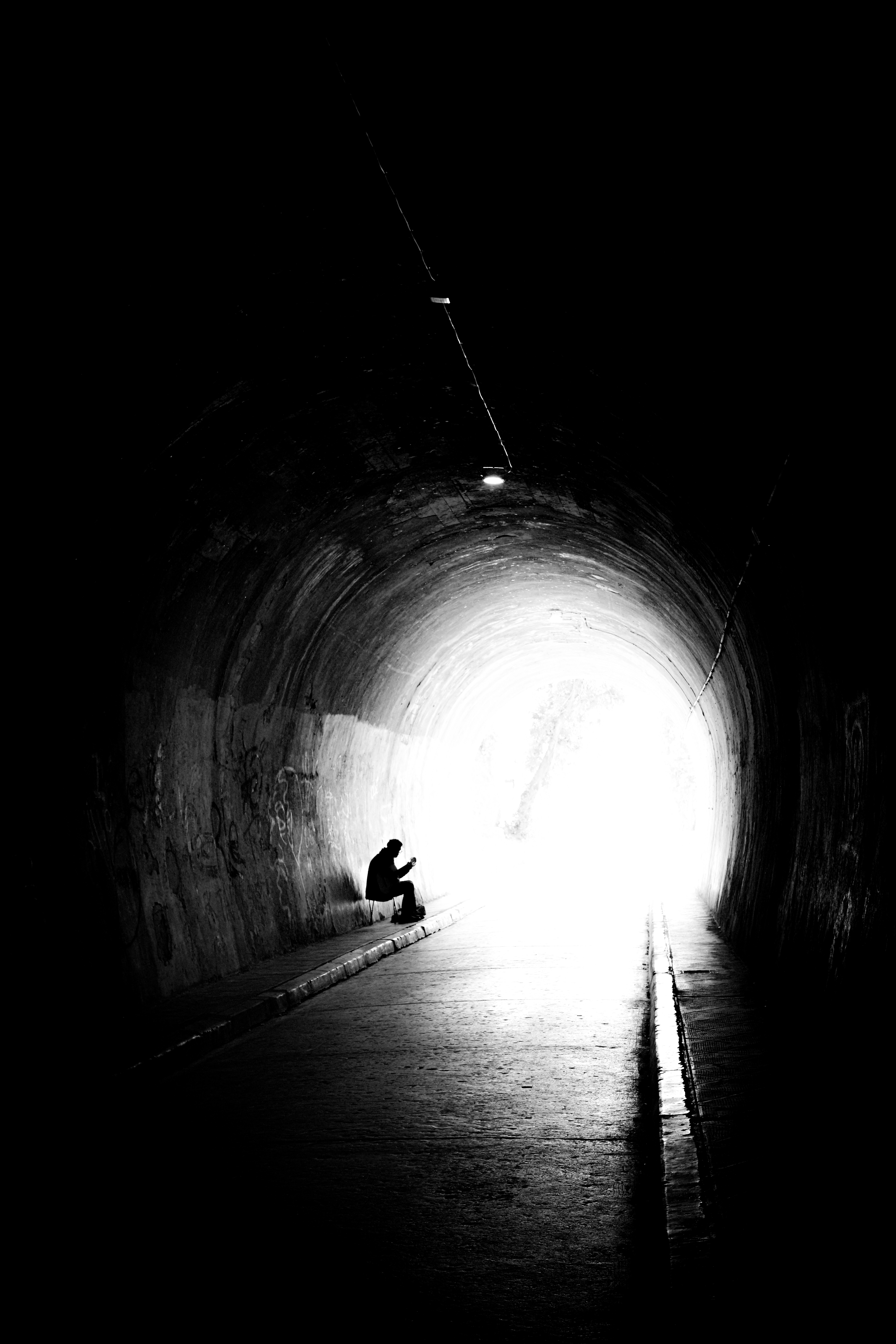 A person sitting in the middle of a dark tunnel
