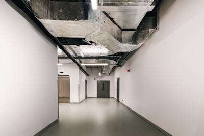 A long hallway with white walls and a black ceiling
