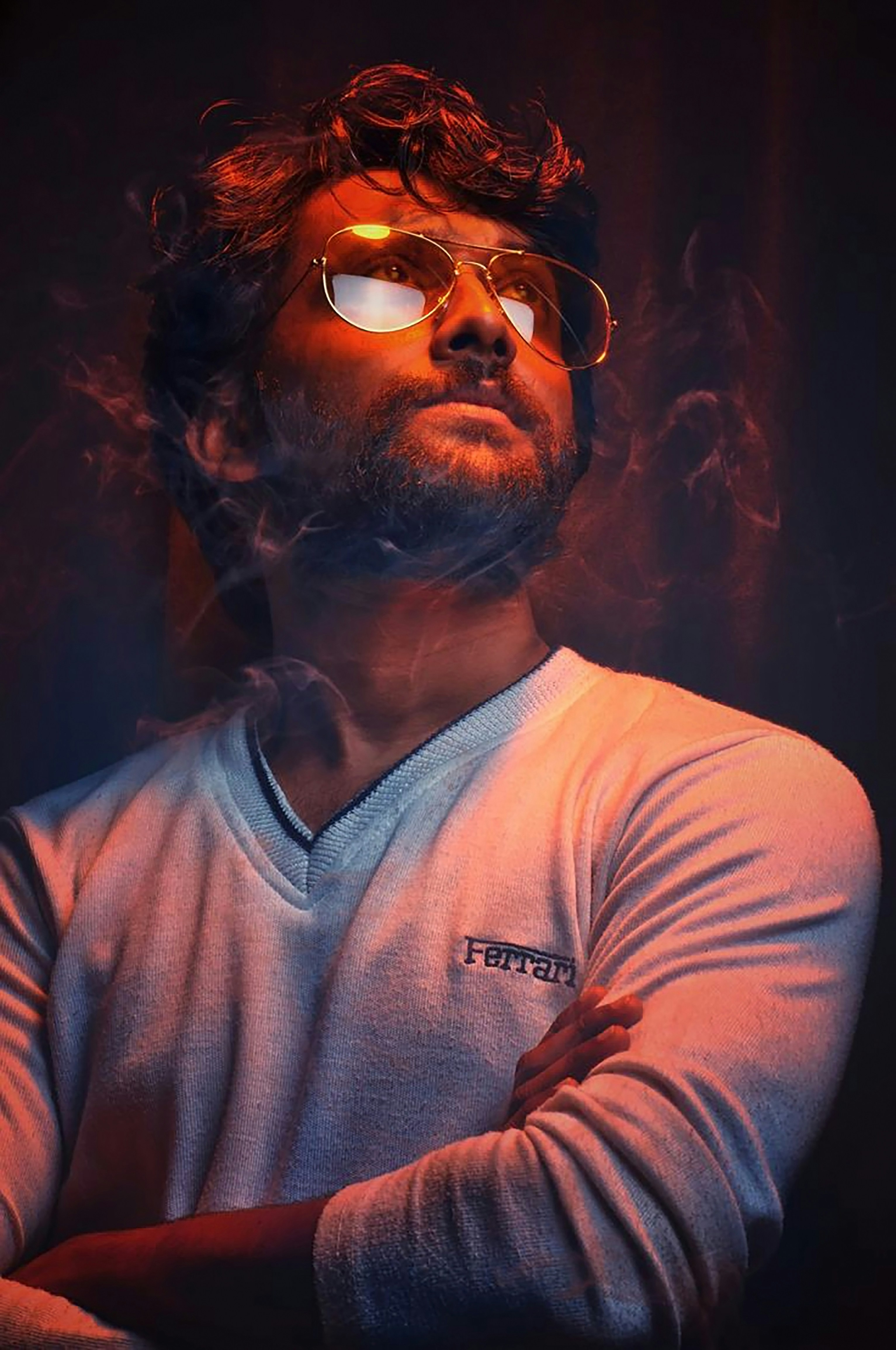 A man with his arms crossed in front of a dark background