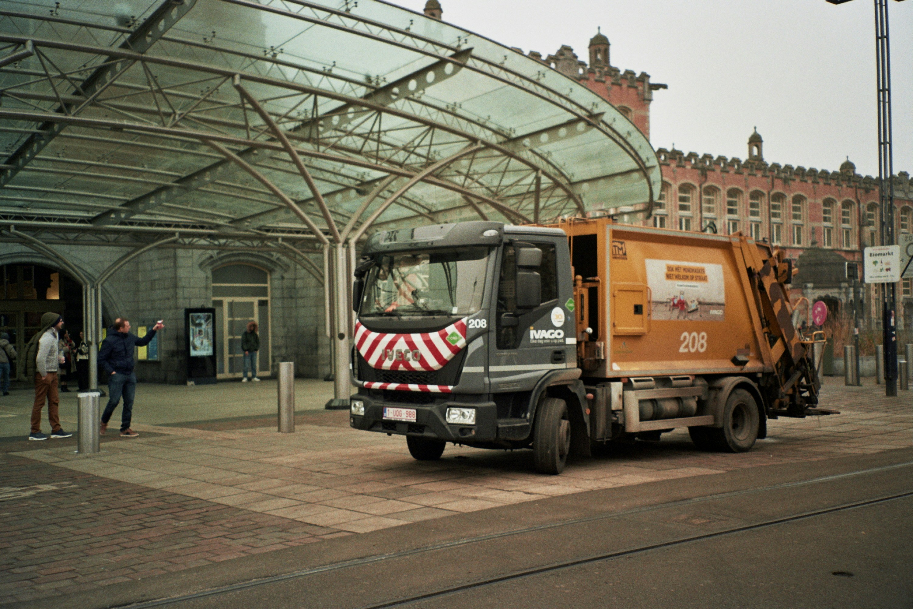 A garbage truck parked in front of a train station