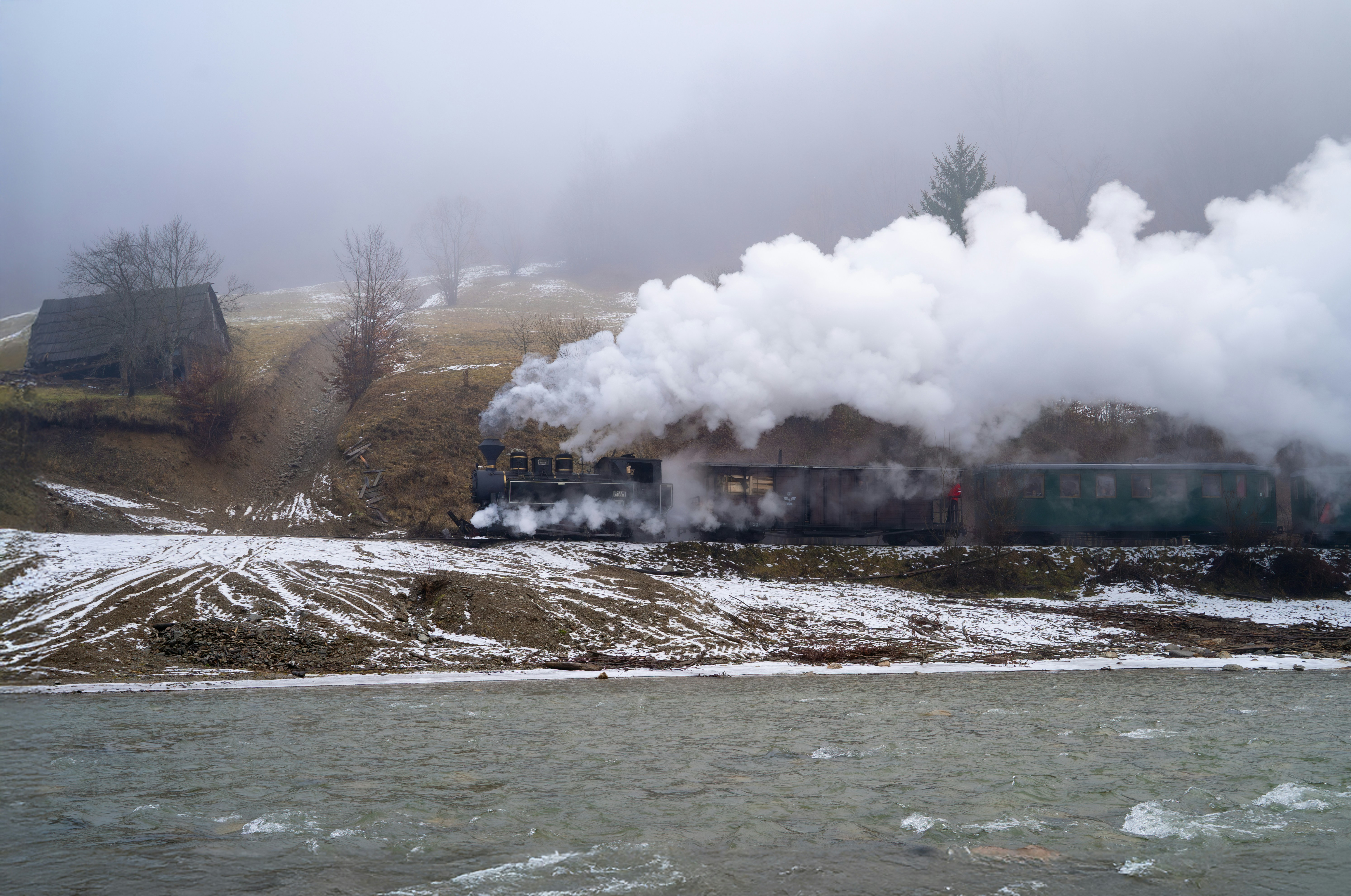 A train traveling down train tracks next to a snow covered hillside