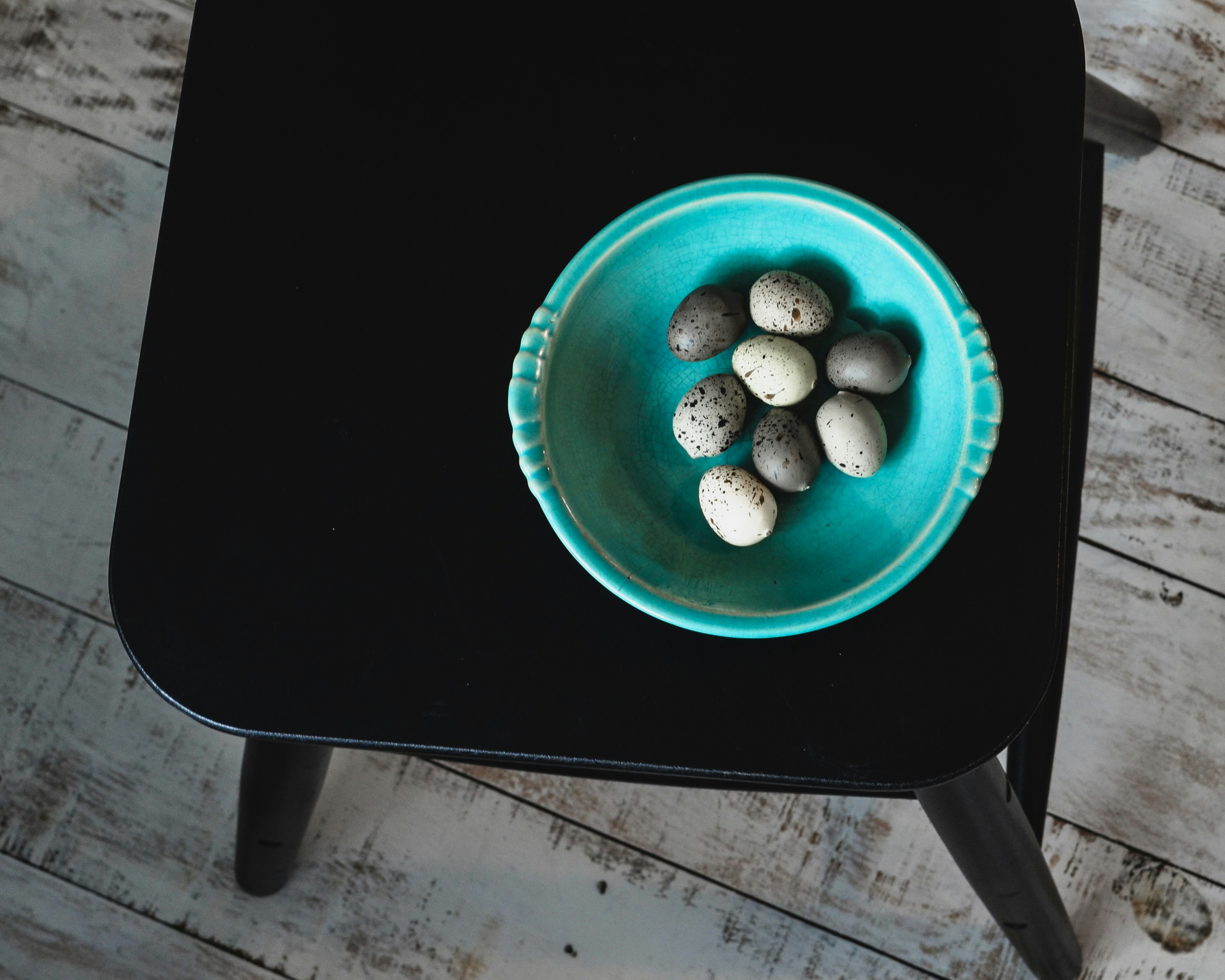 A blue bowl with rocks in it on a black table